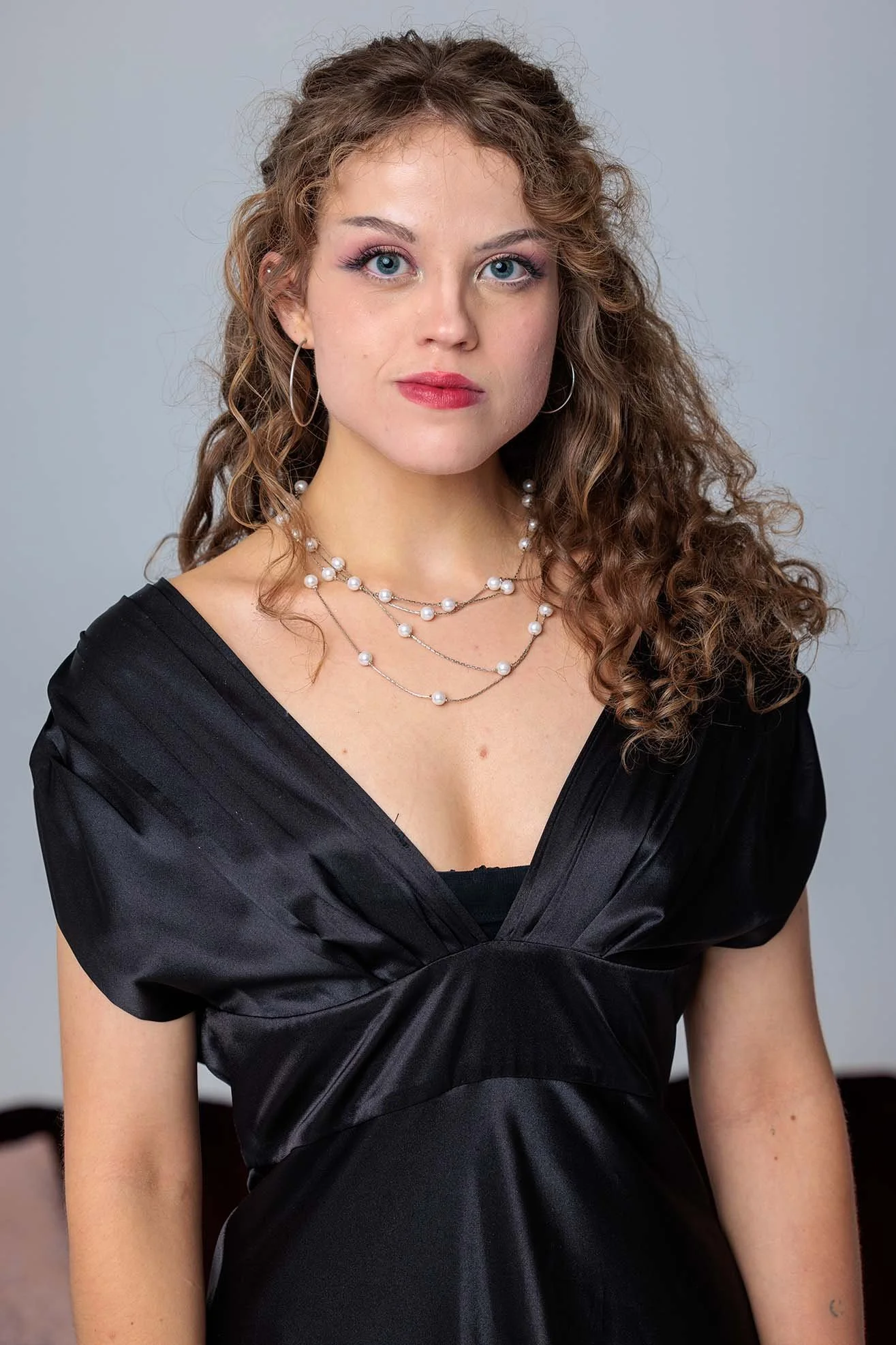 Lucinda Nicholls, smiling wearing a black dress, in her bio photo for Mirabilis Collective.