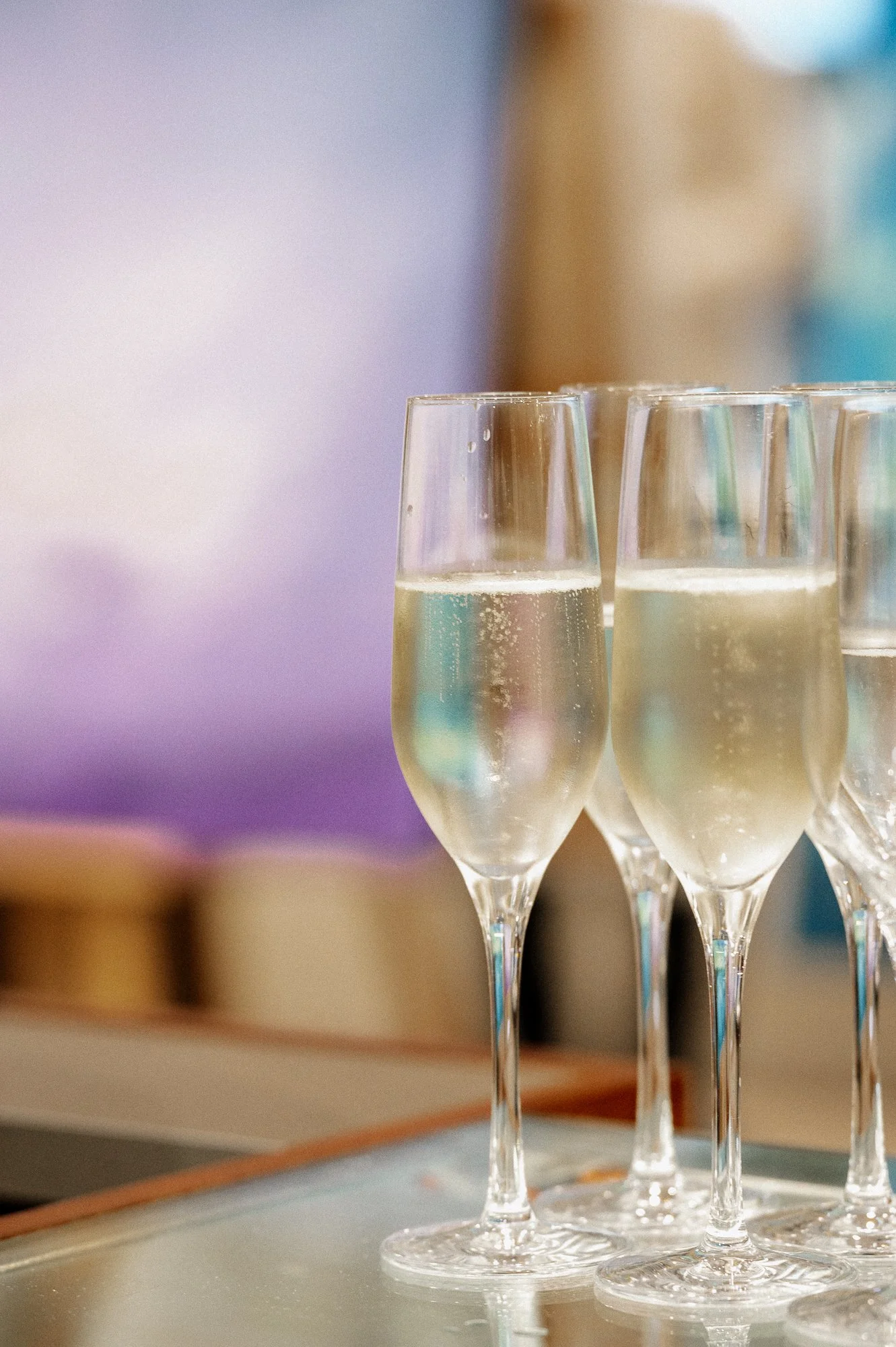 Four glasses of champagne on a table, with a blurred background.