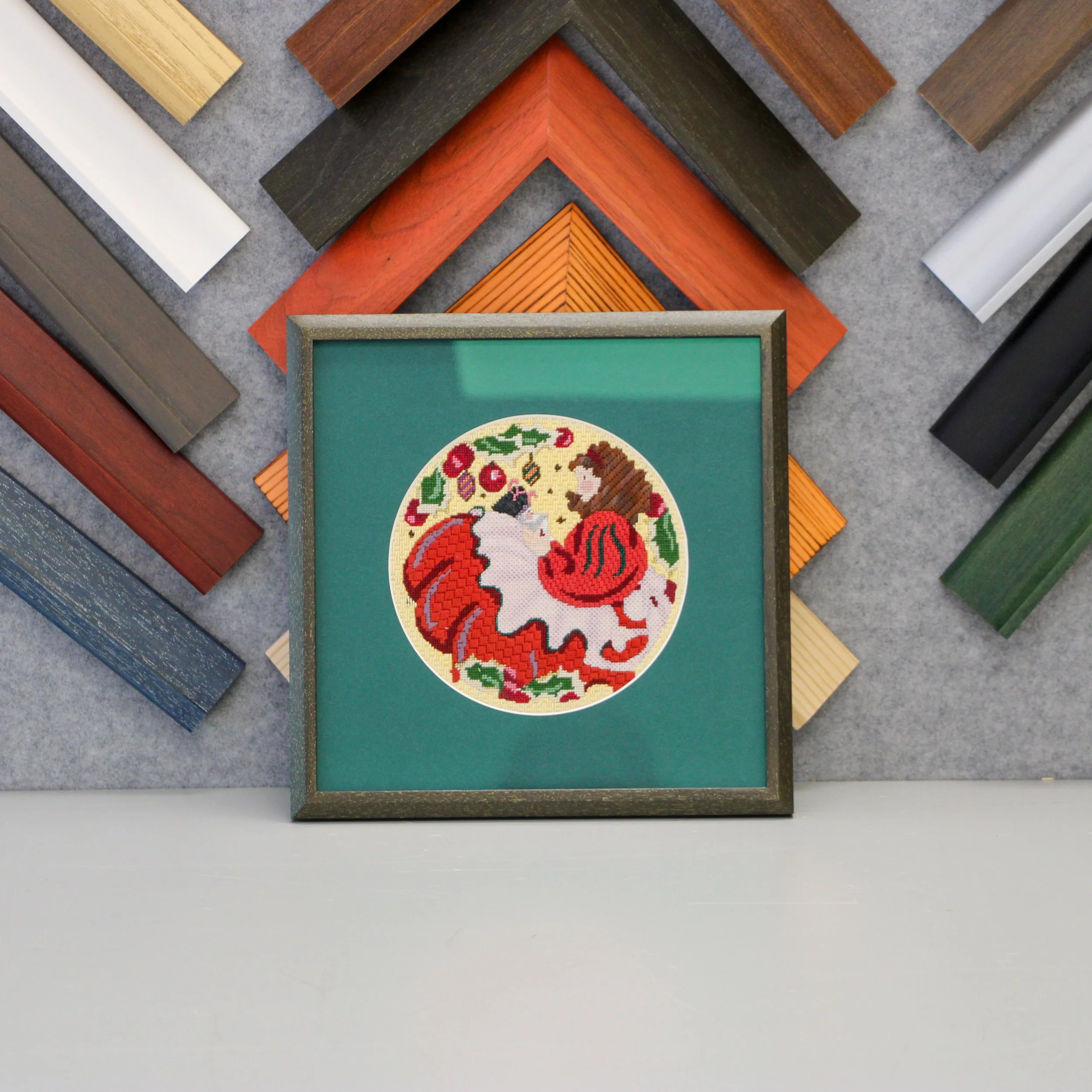 A round needlepoint of a woman in a red dress with a green mat and brown frame.