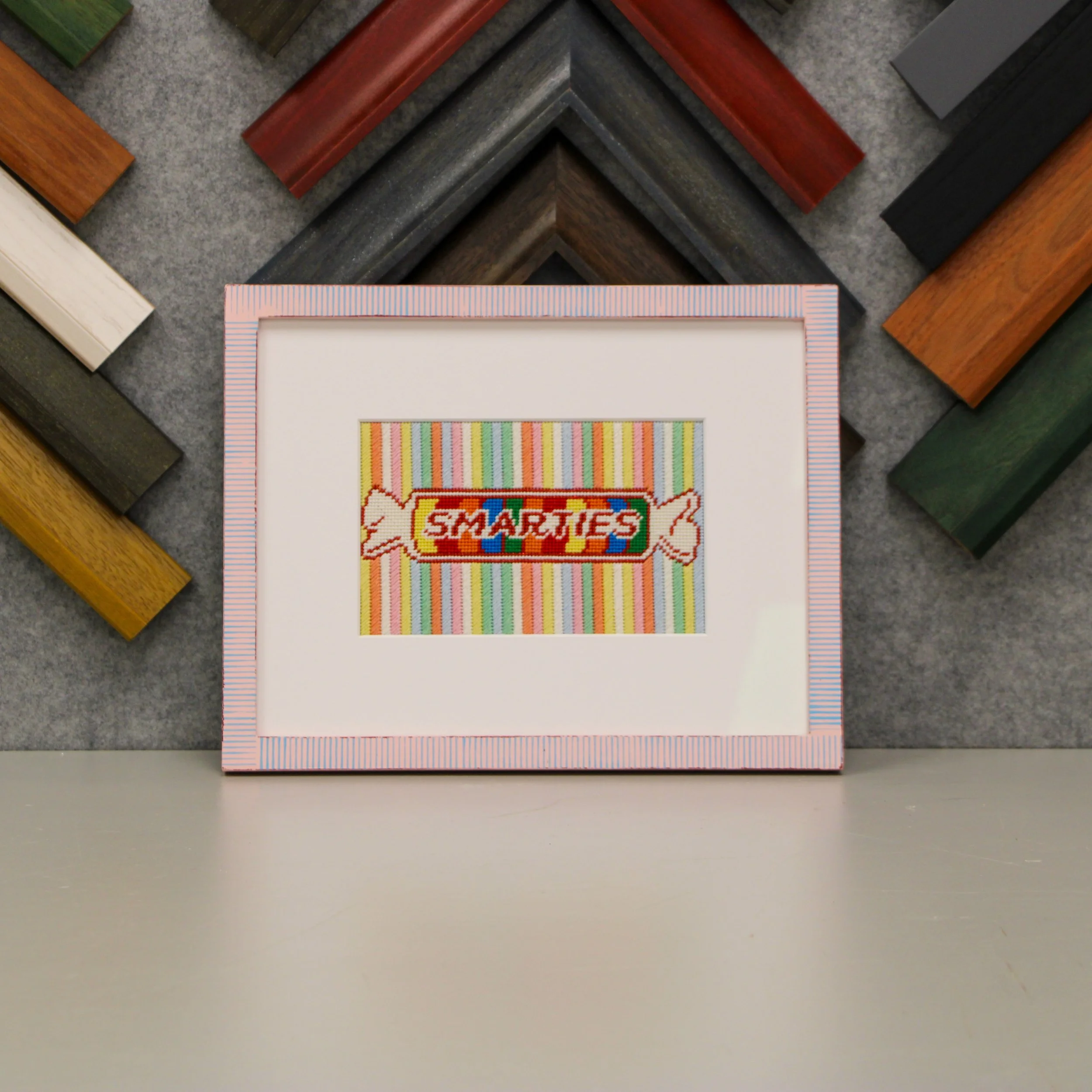 A needlepoint of the candy "Smarties" in a pastel frame.