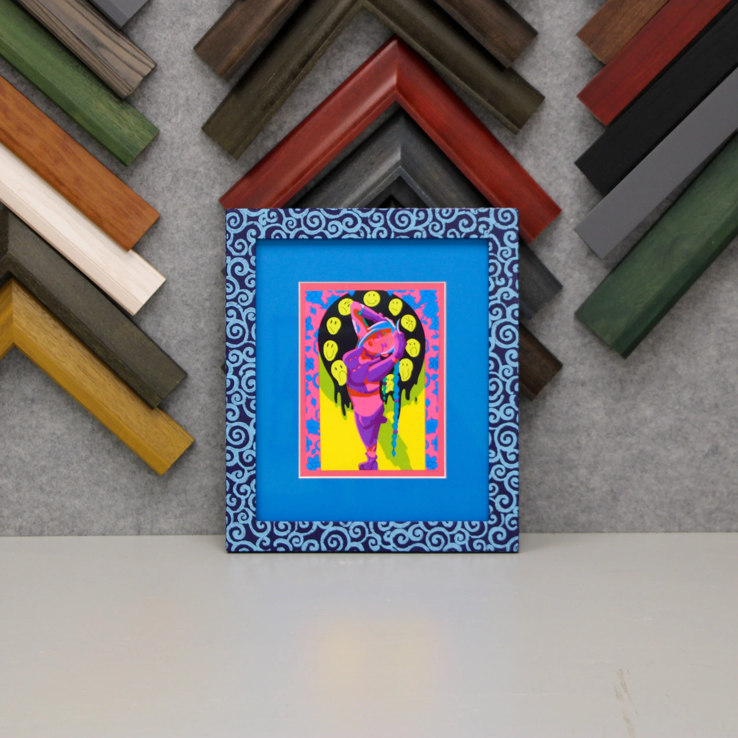An art print of Jinx from Arcane with bright blue and pink mats and a swirly blue frame.