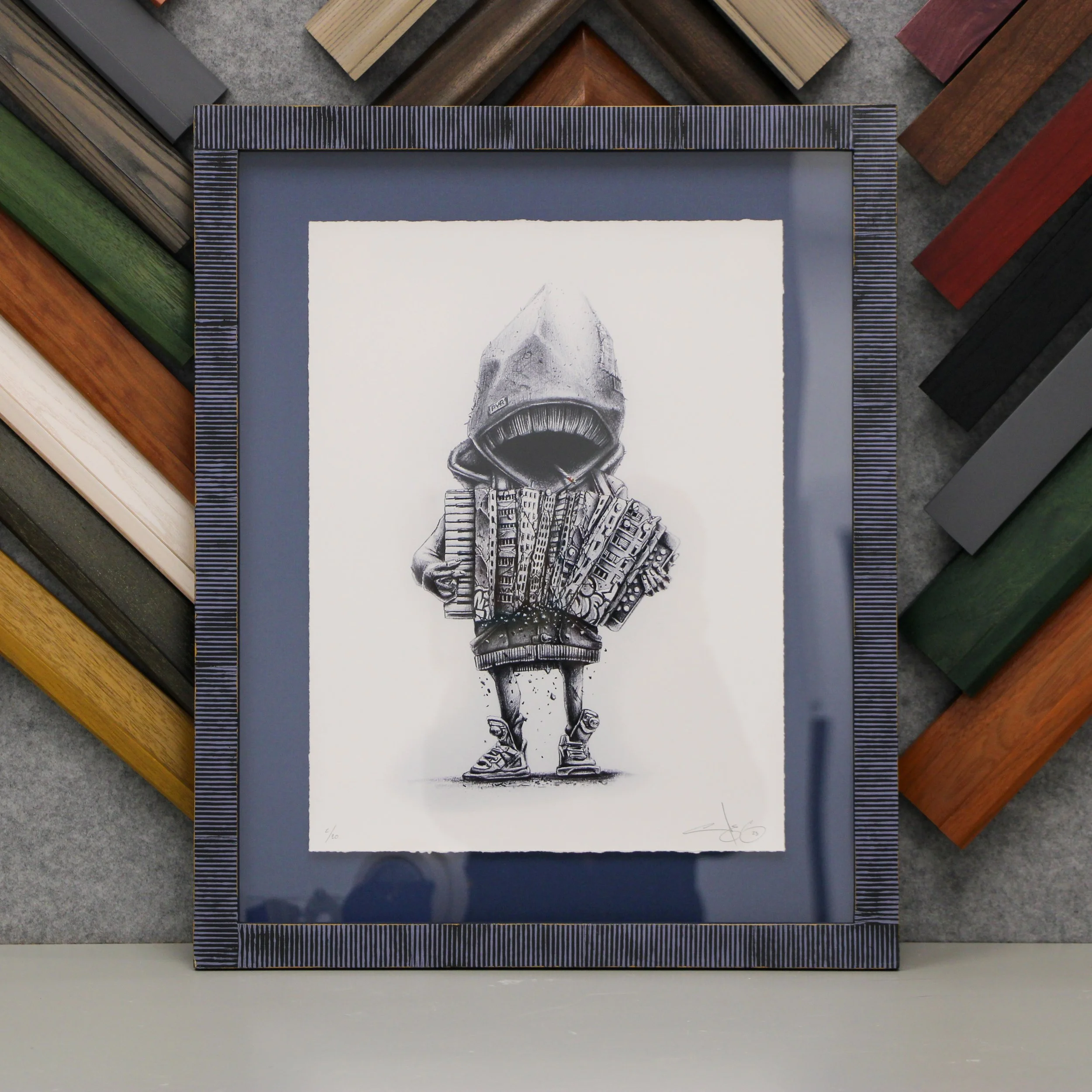A print of a hooded figure with a blue mat and dark grey textured frame.