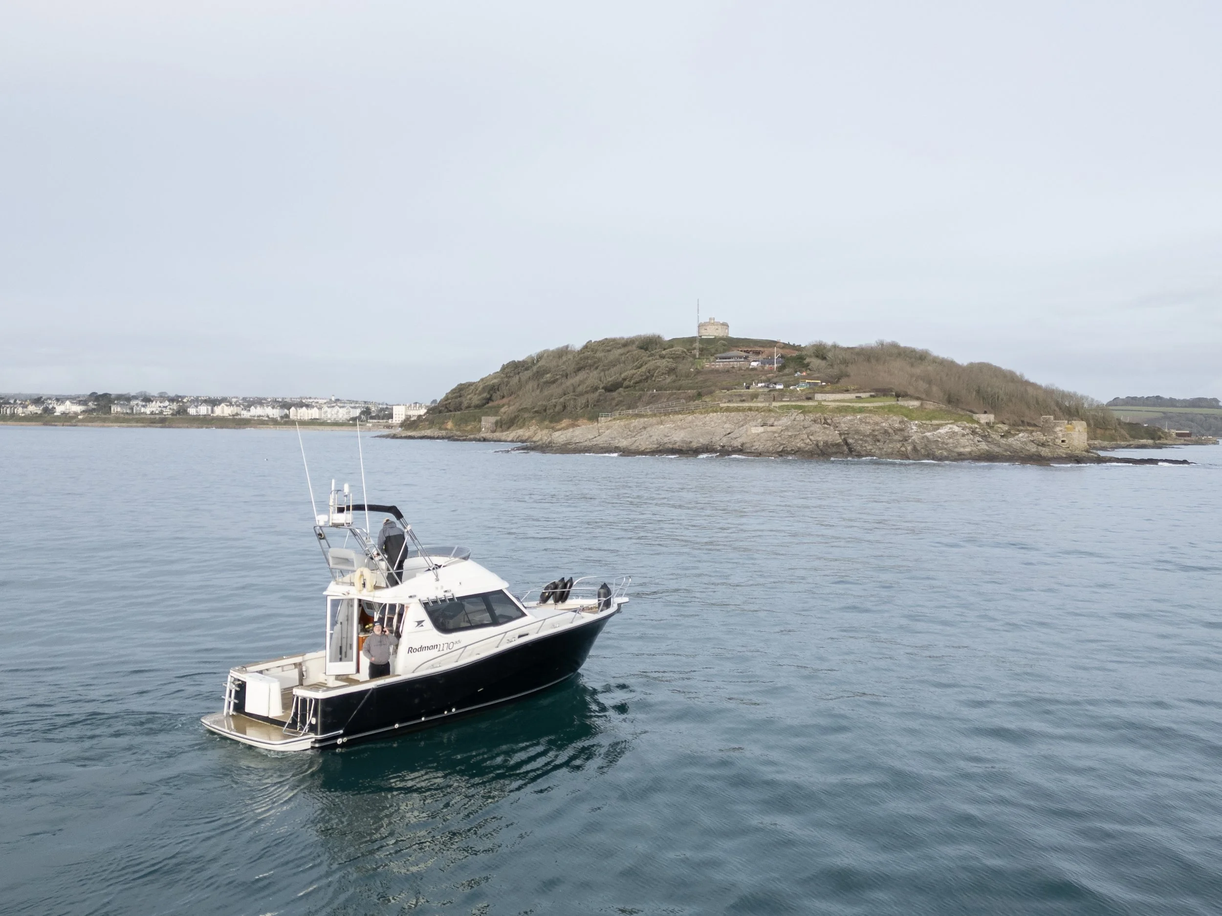 A motorboat sailing on calm water with a hilly island in the background