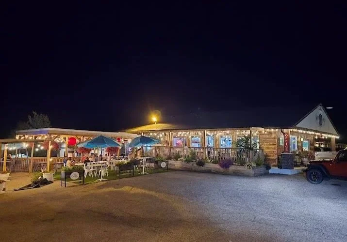 Wide exterior view of Vintage Block Inn & Suites in Okoboji, Iowa, featuring the motel buildings, central gazebo, landscaped grounds, ample parking, and pedal carts available for guests on a beautiful clear summer night.