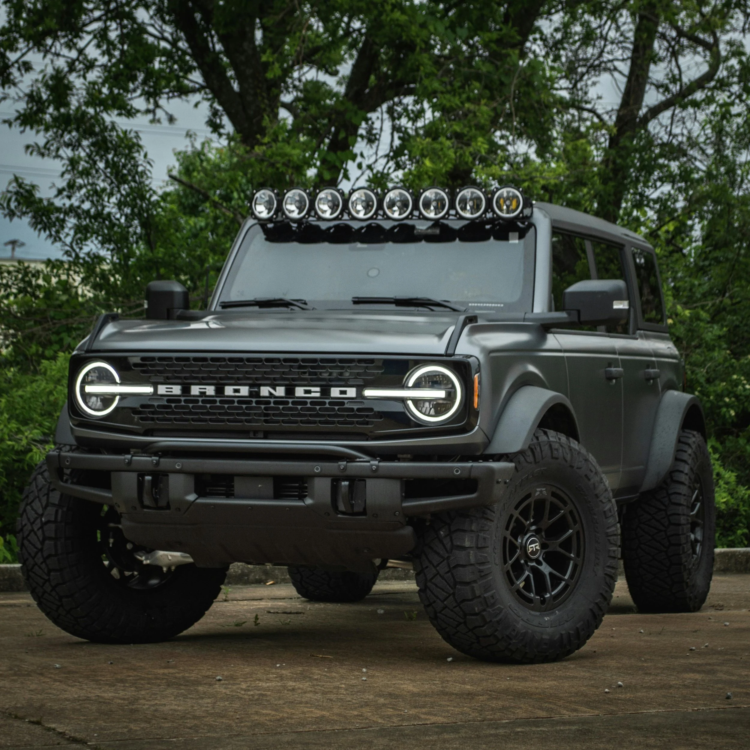 A matte black Ford Bronco SUV with off-road tires, a front grille with 
