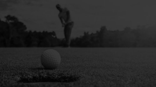 A person preparing to putt on a golf course with a golf ball near the hole in the foreground.