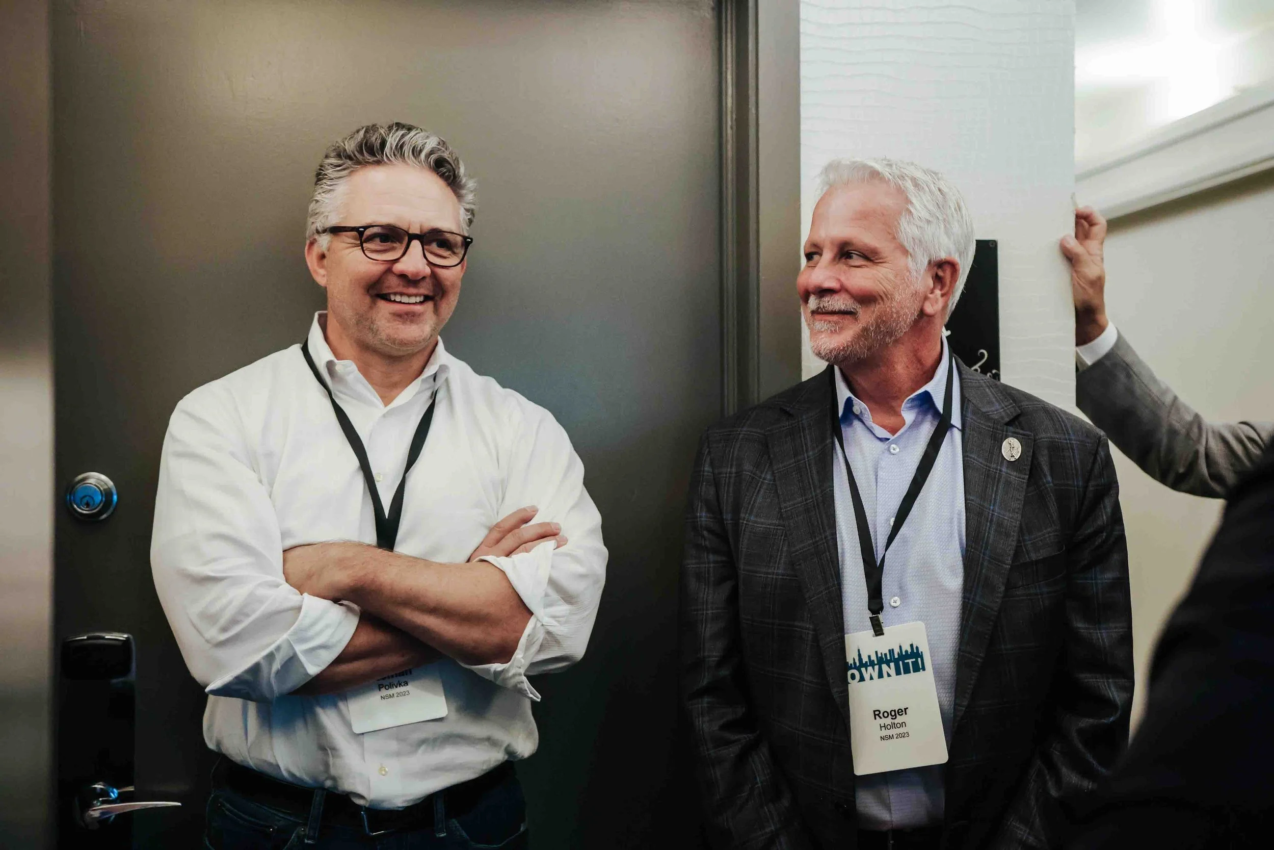Two men standing and looking at others talking