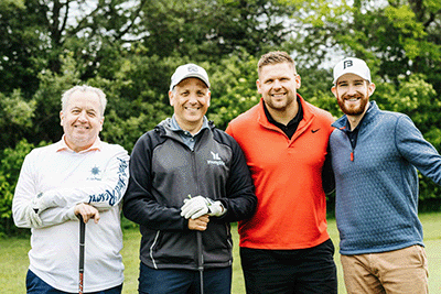 four men standing and posing at golf tournament