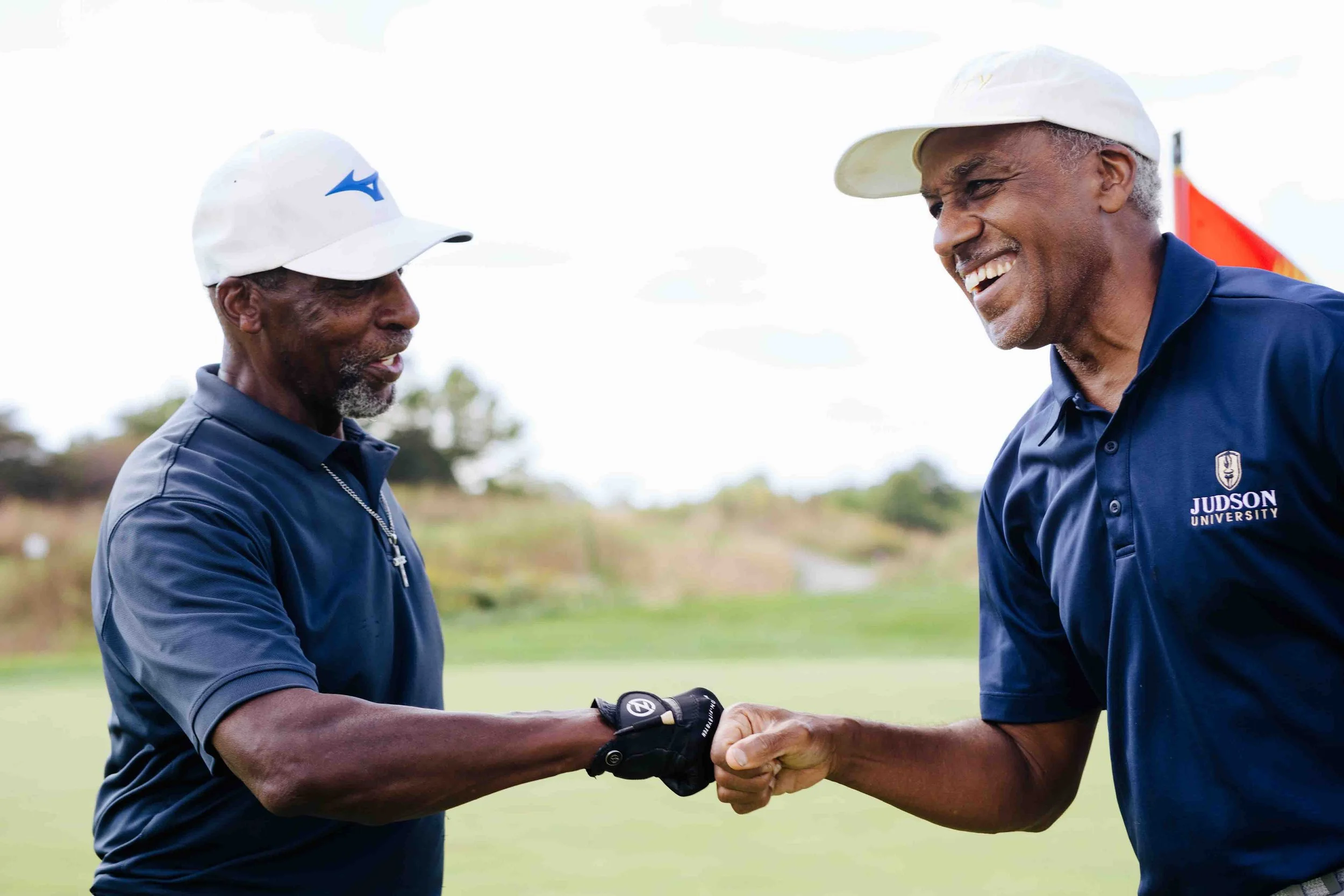 Two african american men at golf event smiling and dabbing