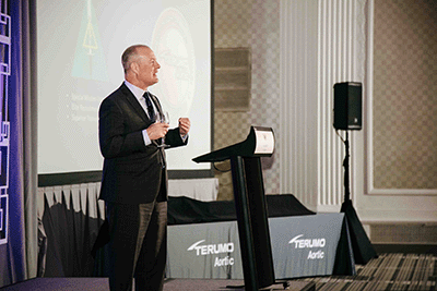 Man talking on stage at a conference to an audience