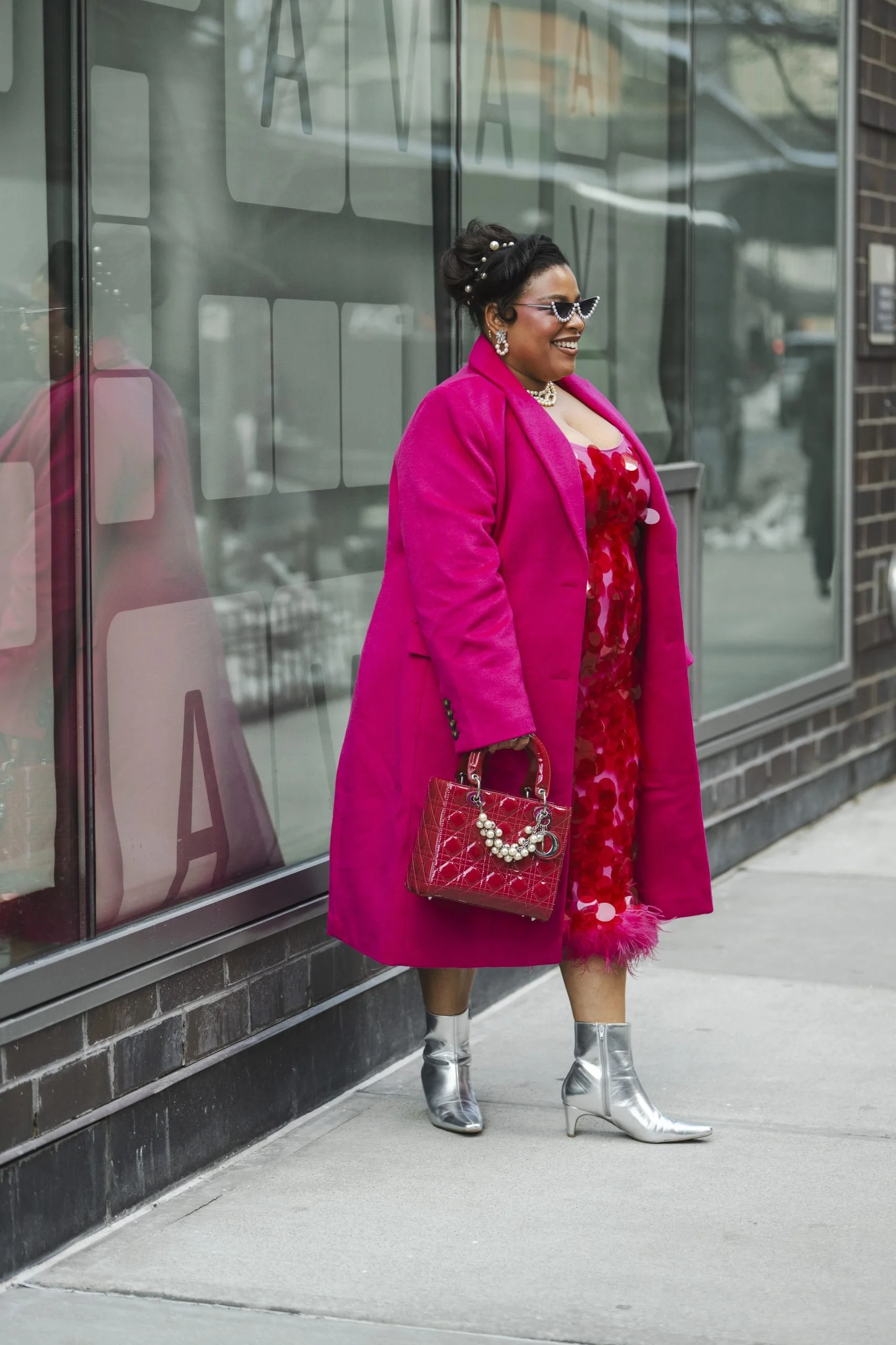 Greivy styled in a statement pink coat and metallic boots during New York Fashion Week FW26 street style coverage on ESSENCE.com.