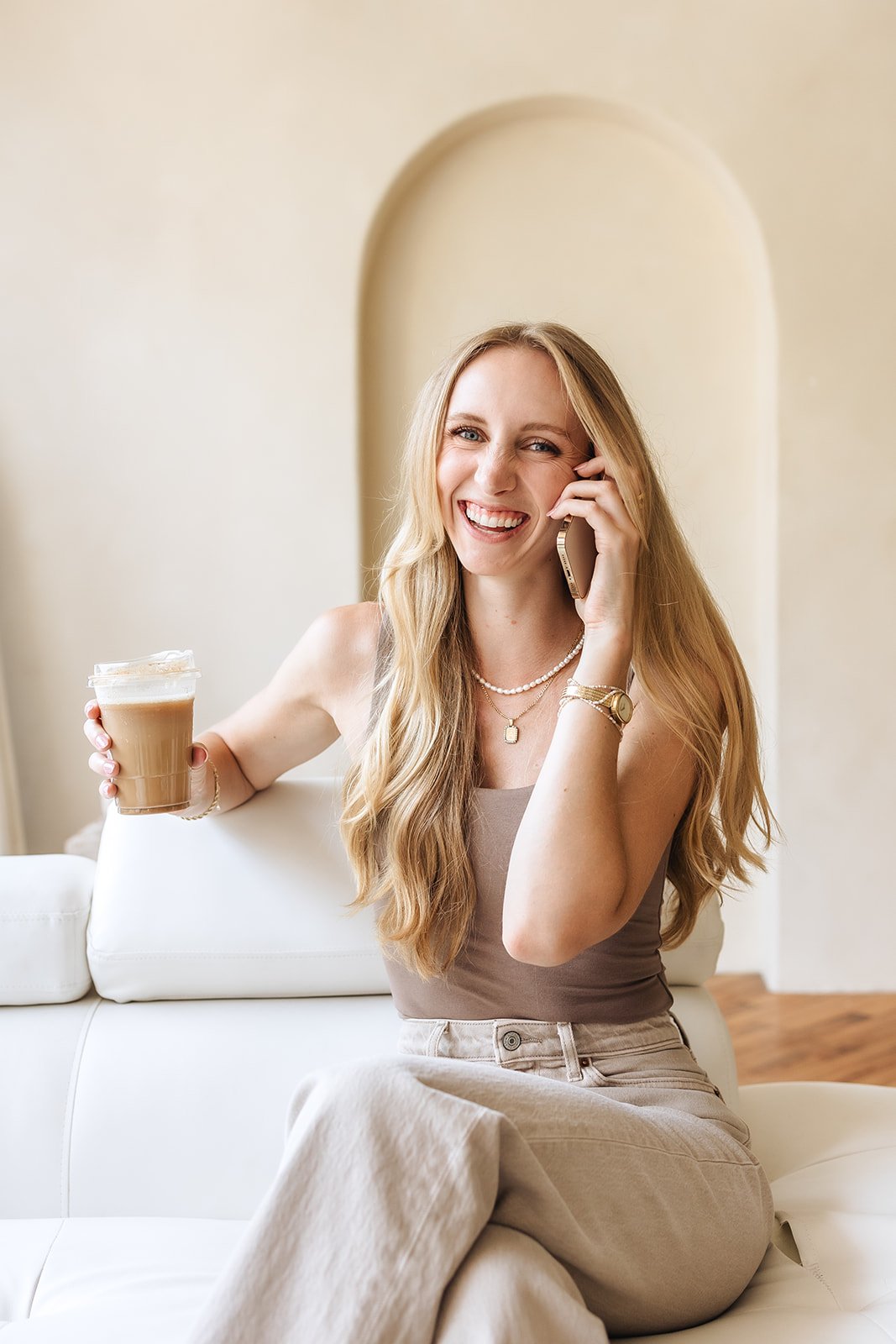 Woman holding a coffee, talking on the phone, and smiling