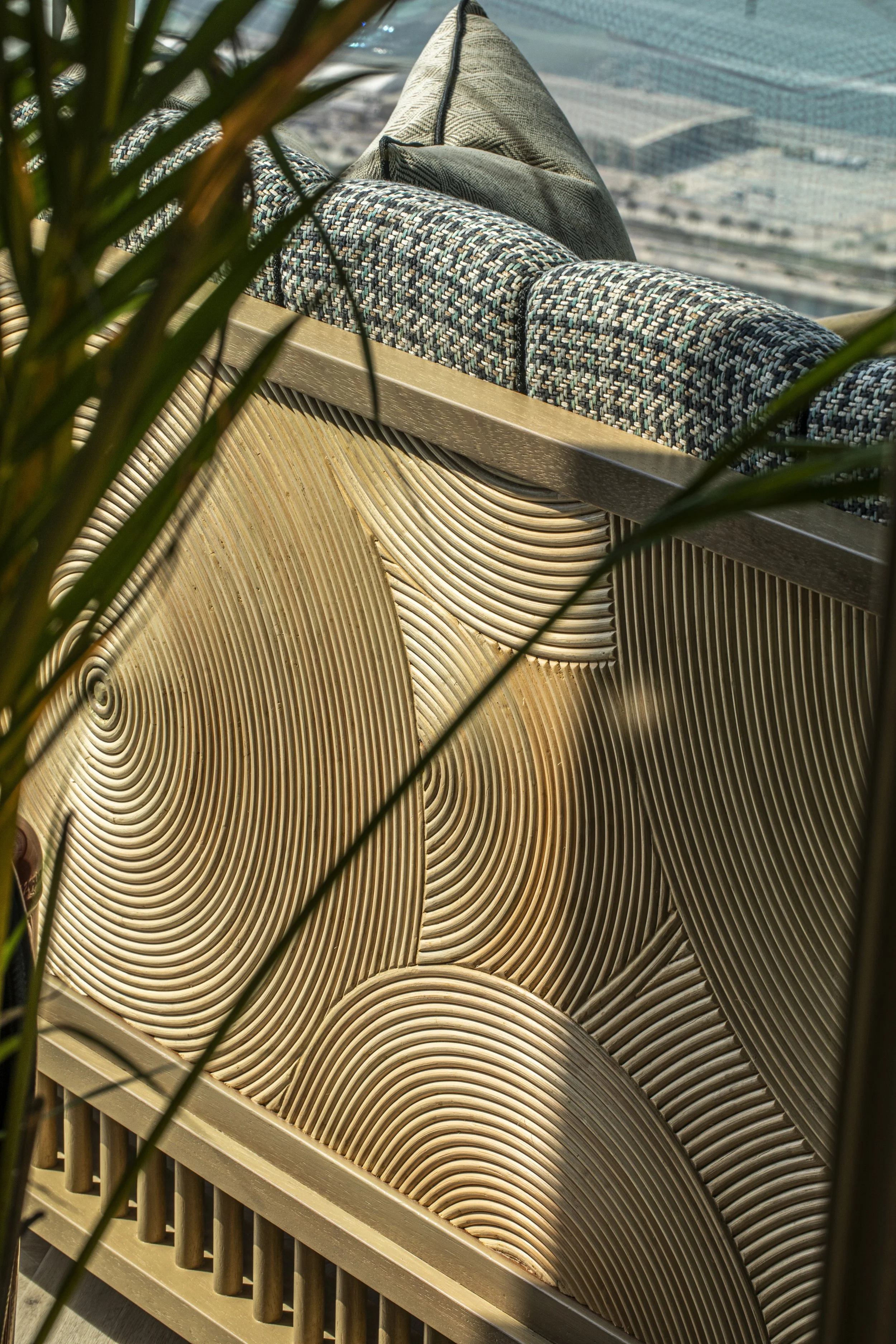 A close up of the back of a sofa at Tattu Dubia Sky Pool. The back is made up of handmade bamboo marquetry in concentric circles.