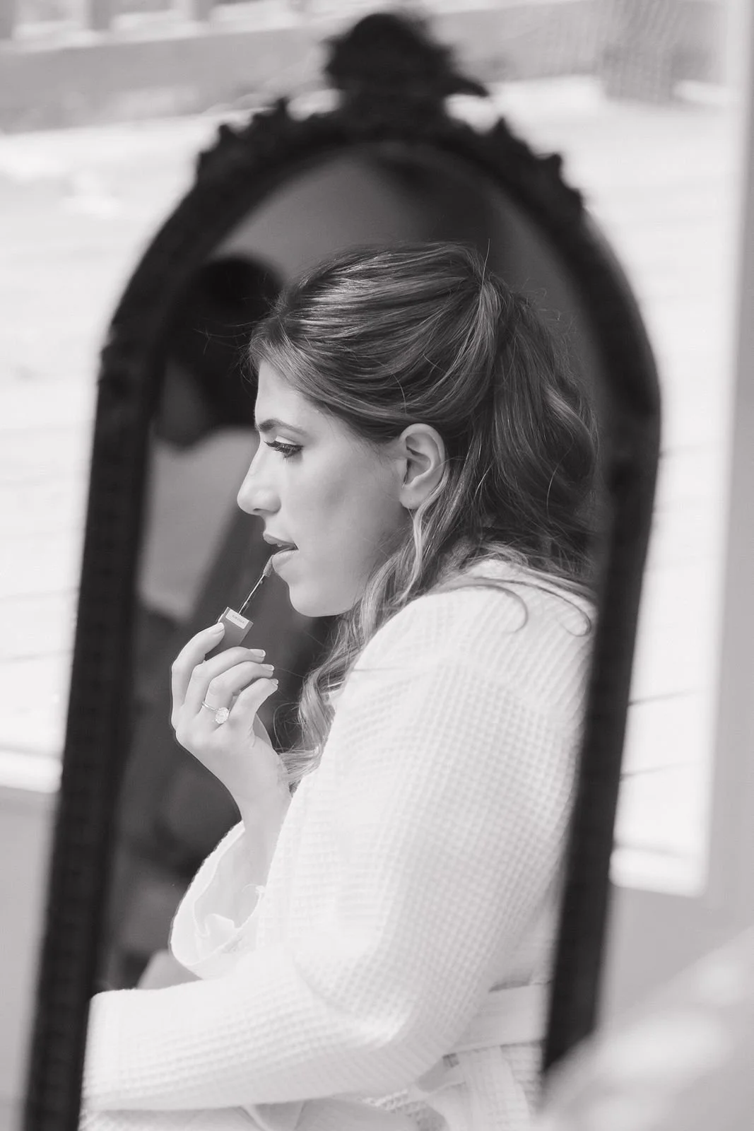 A bride applying lip gloss as she is getting ready for her wedding day at the Wabeek Country Club.