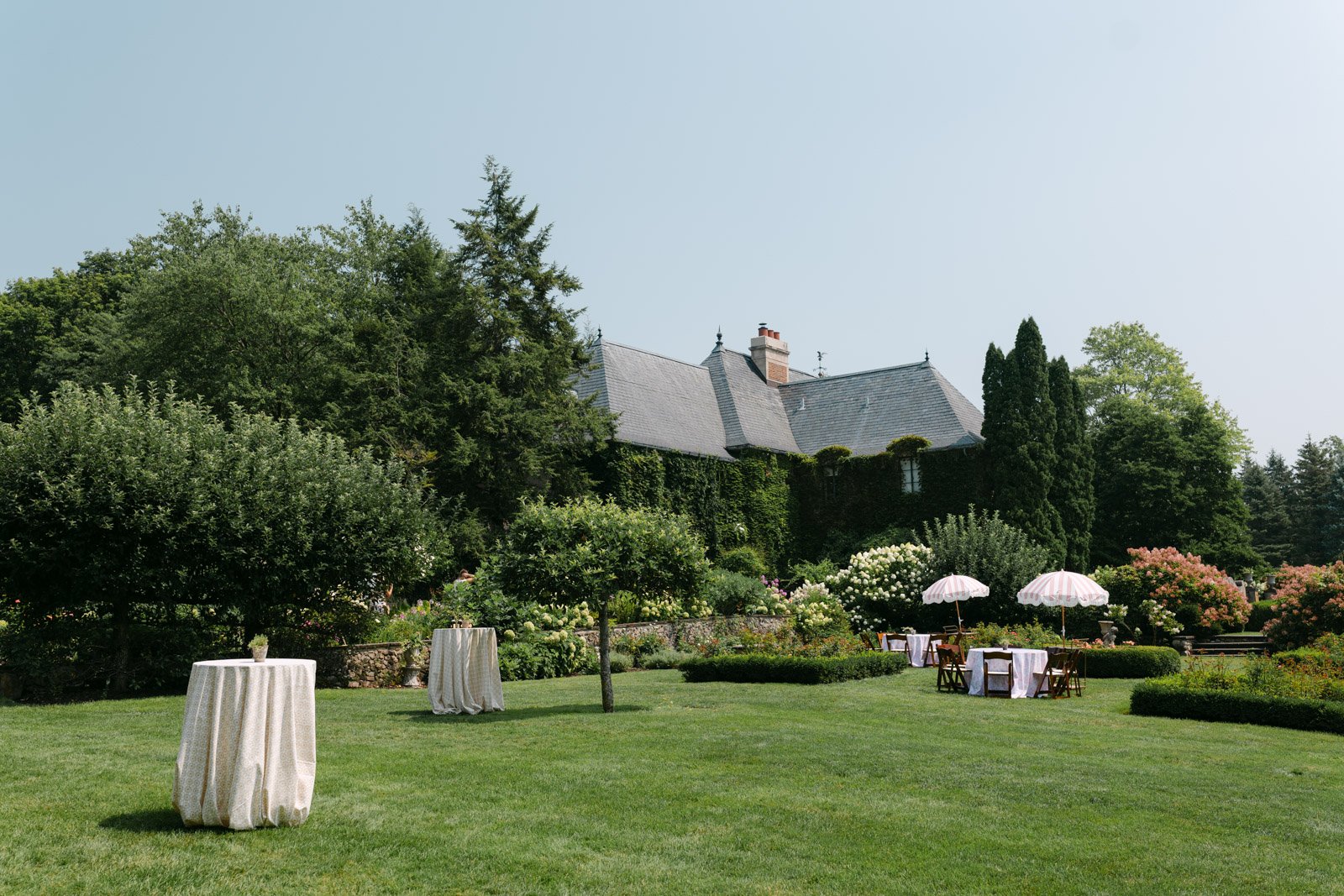 A large, french inspired estate wedding venue with a large yard full of grass and gardens.