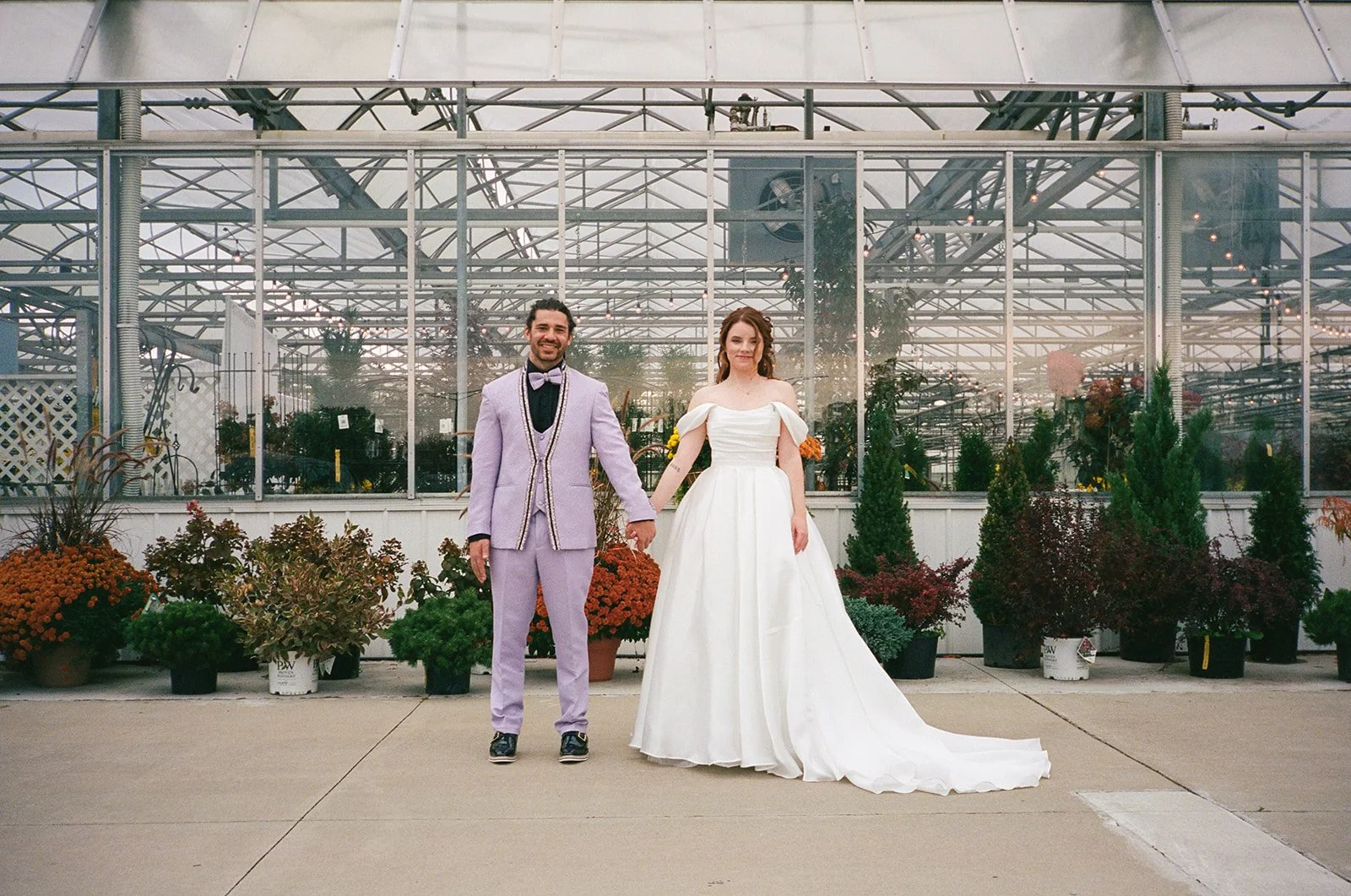 Film photo of the bride and groom holding hands in front of Abele Greenhouse in Saginaw, Michigan.