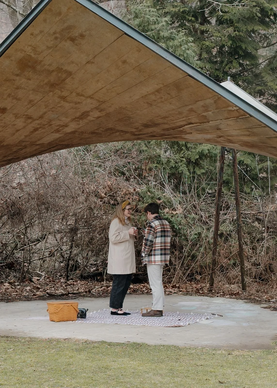 Couple enjoying tea together at picnic after proposal in Nichols Arboretum Ann Arbor park under pavilion structure