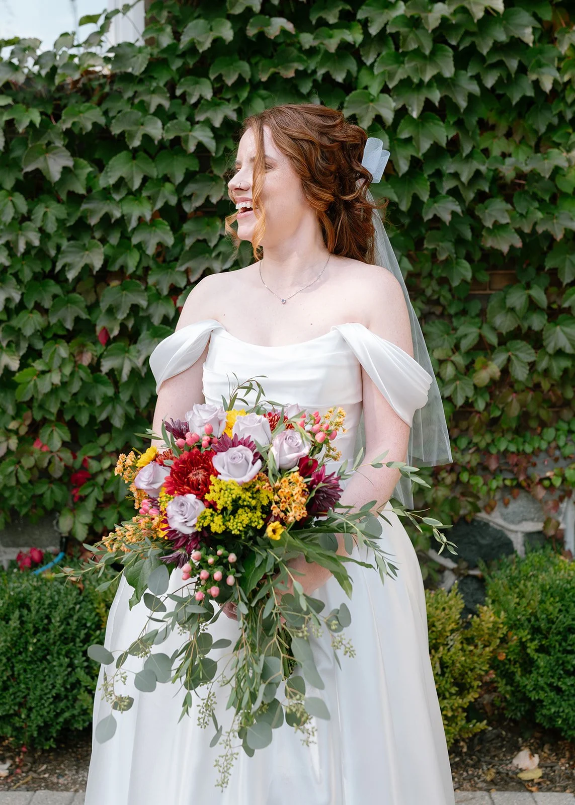 Bride smiling while holding a colorful wedding bouquet.