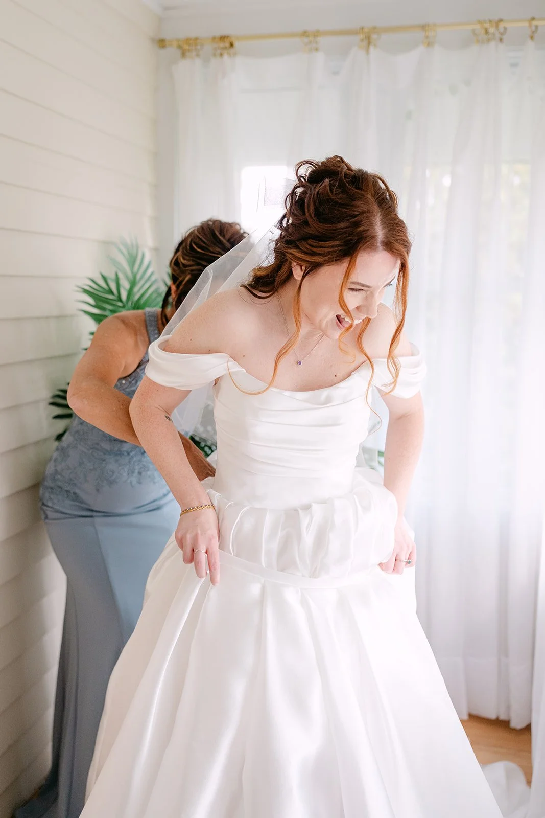 Vride laughing as her mother helps her into her dress.