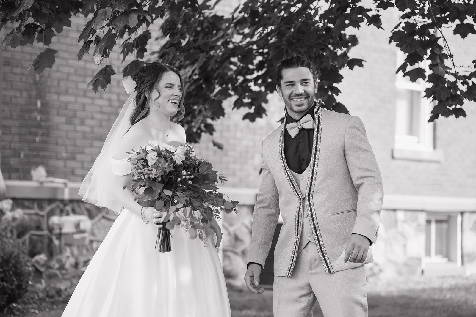 Black and white photo of a bride and groom smiling after their first look outside of Brownstone Haus in Frankenmuth, Michigan.
