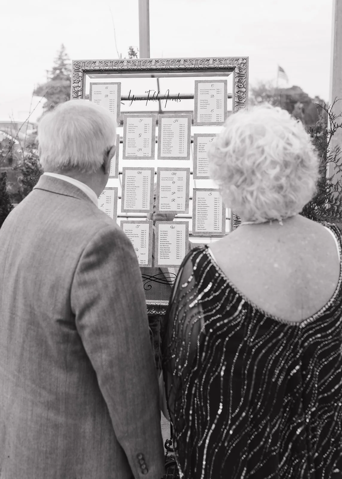 Black and white photo of guests looking over the seating chart.