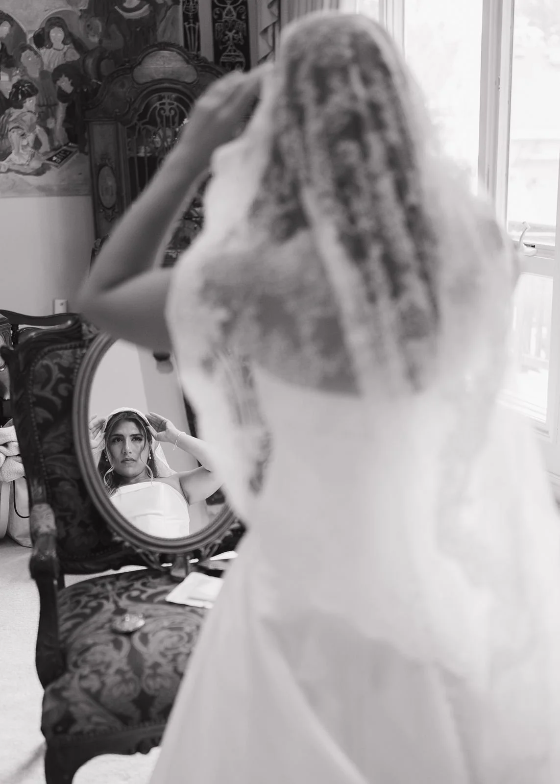 A bride fixing her veil in the mirror before getting married at the Wabeek Country Club.