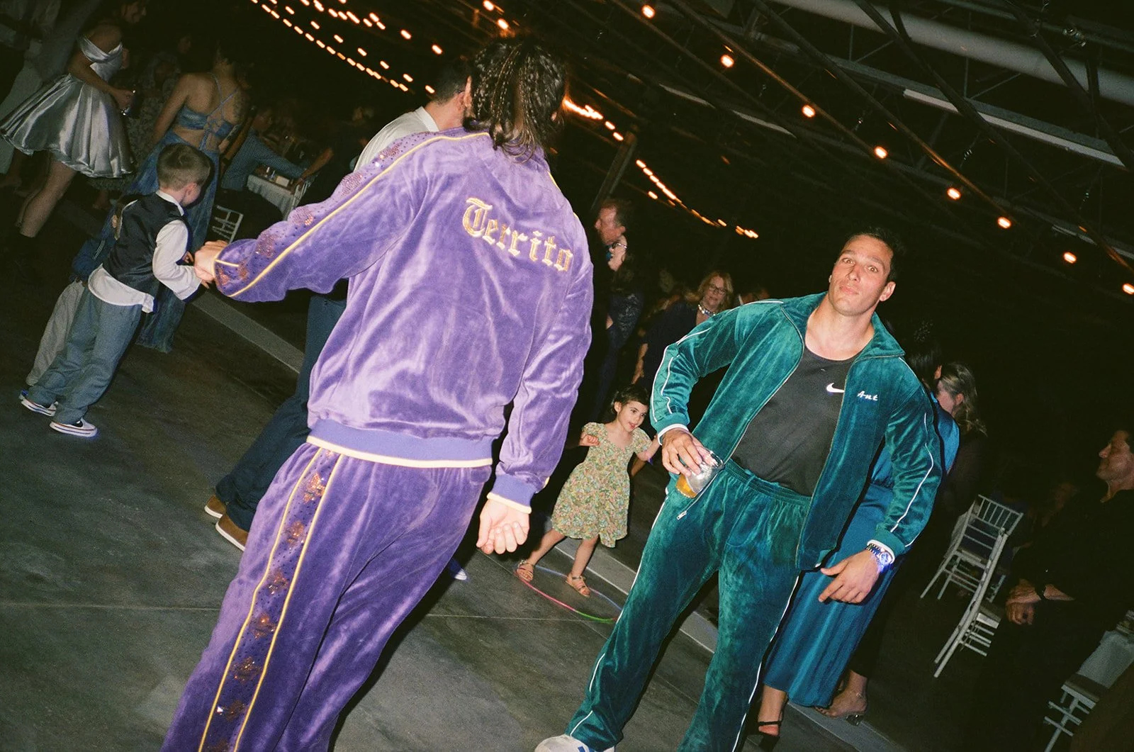 Film photo of the groom and a groomsmen dancing in colorful Velour Tracksuits