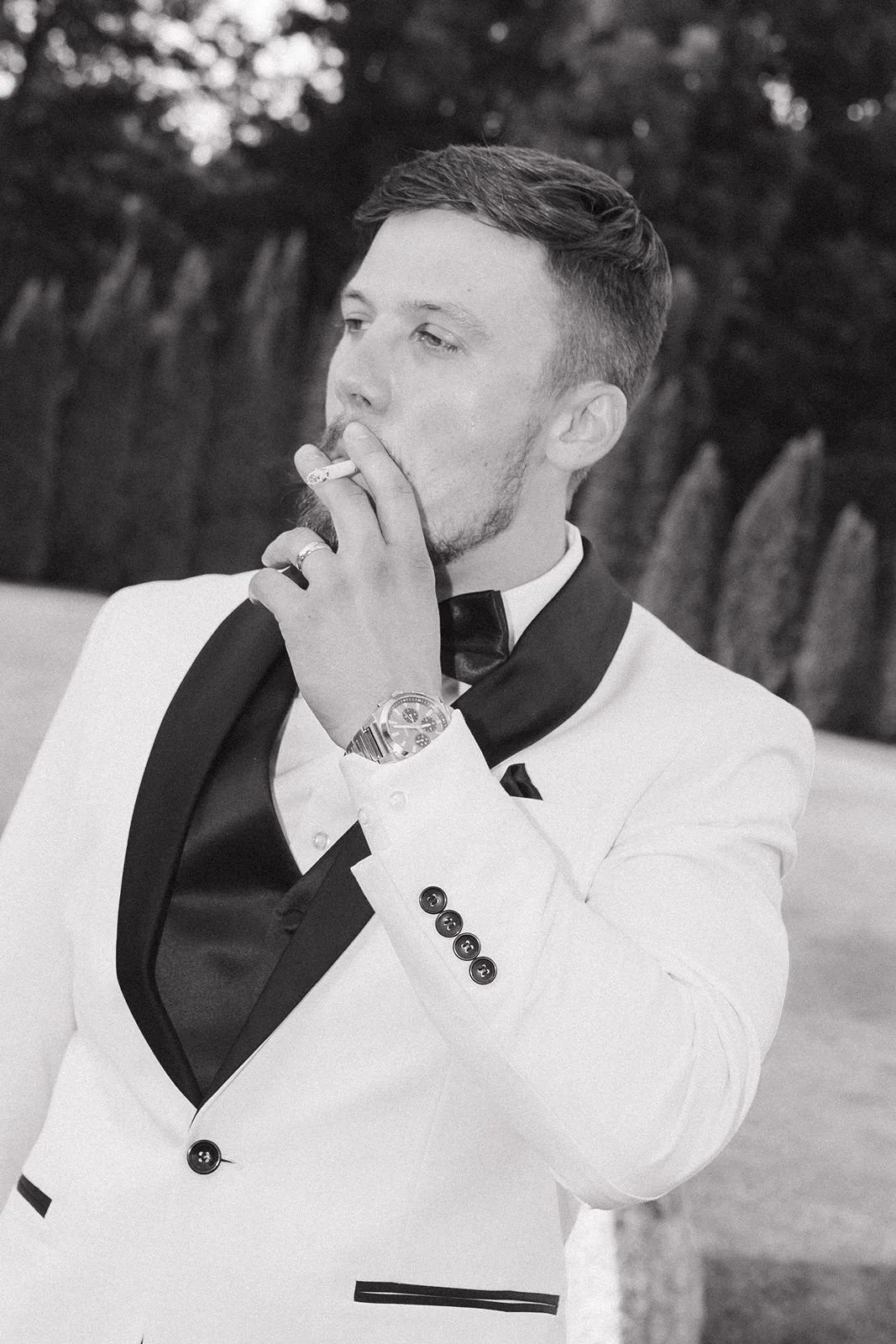 A groom smoking a cigarette while wearing his new wedding band.