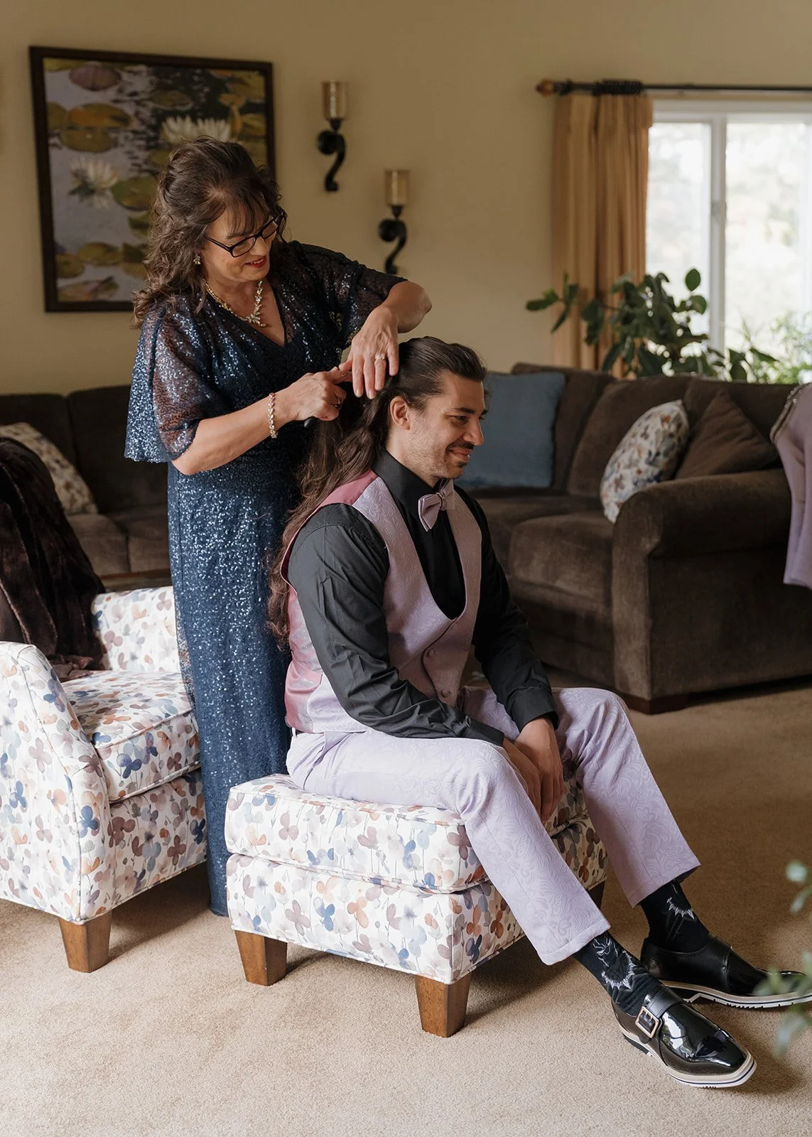 Groom getting his long hair styled by his mother.