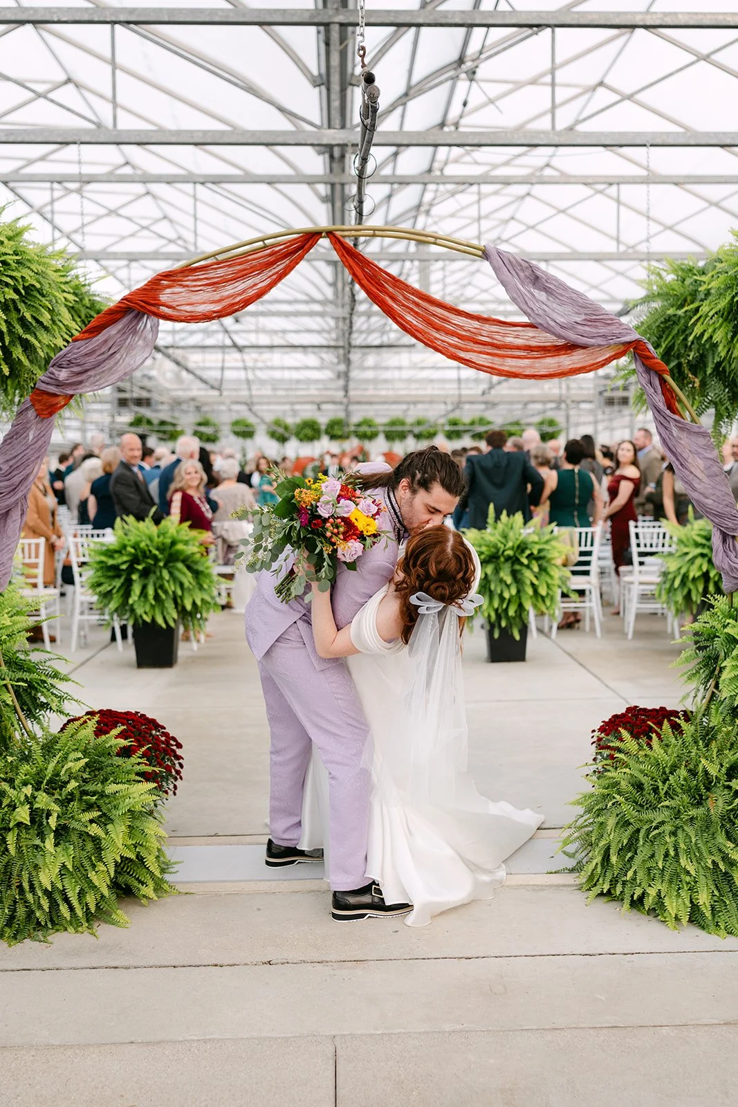 Bride and grooms dip kiss at the end of the aisle after their Abele Greenhouse wedding ceremony.