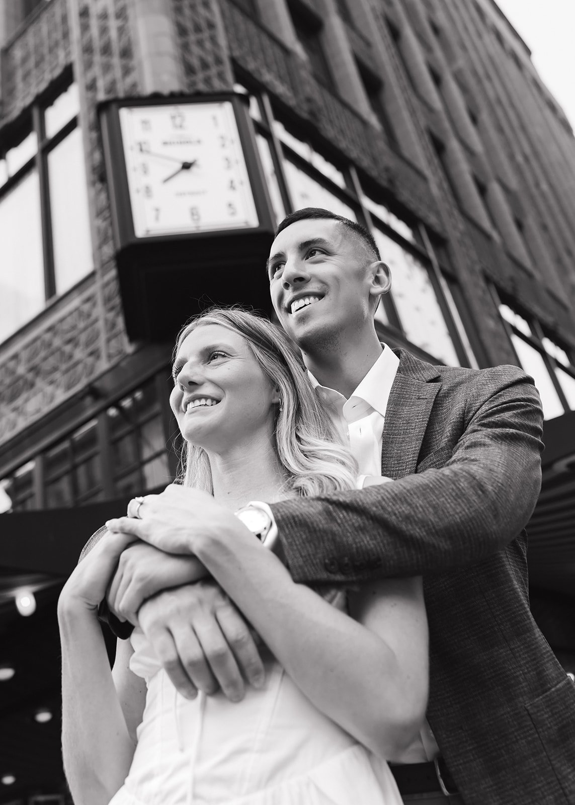 Black and white photo of a bride and groom posing under the Shinola clock.
