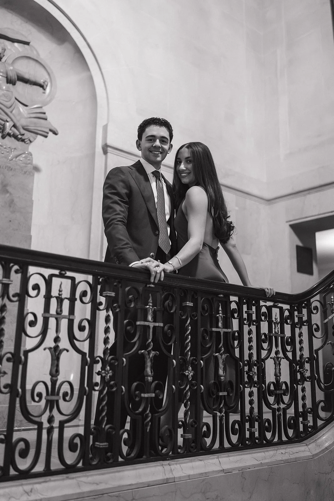 Black and white photo of a couple posing against a railing at The Detroit Athletic Club.