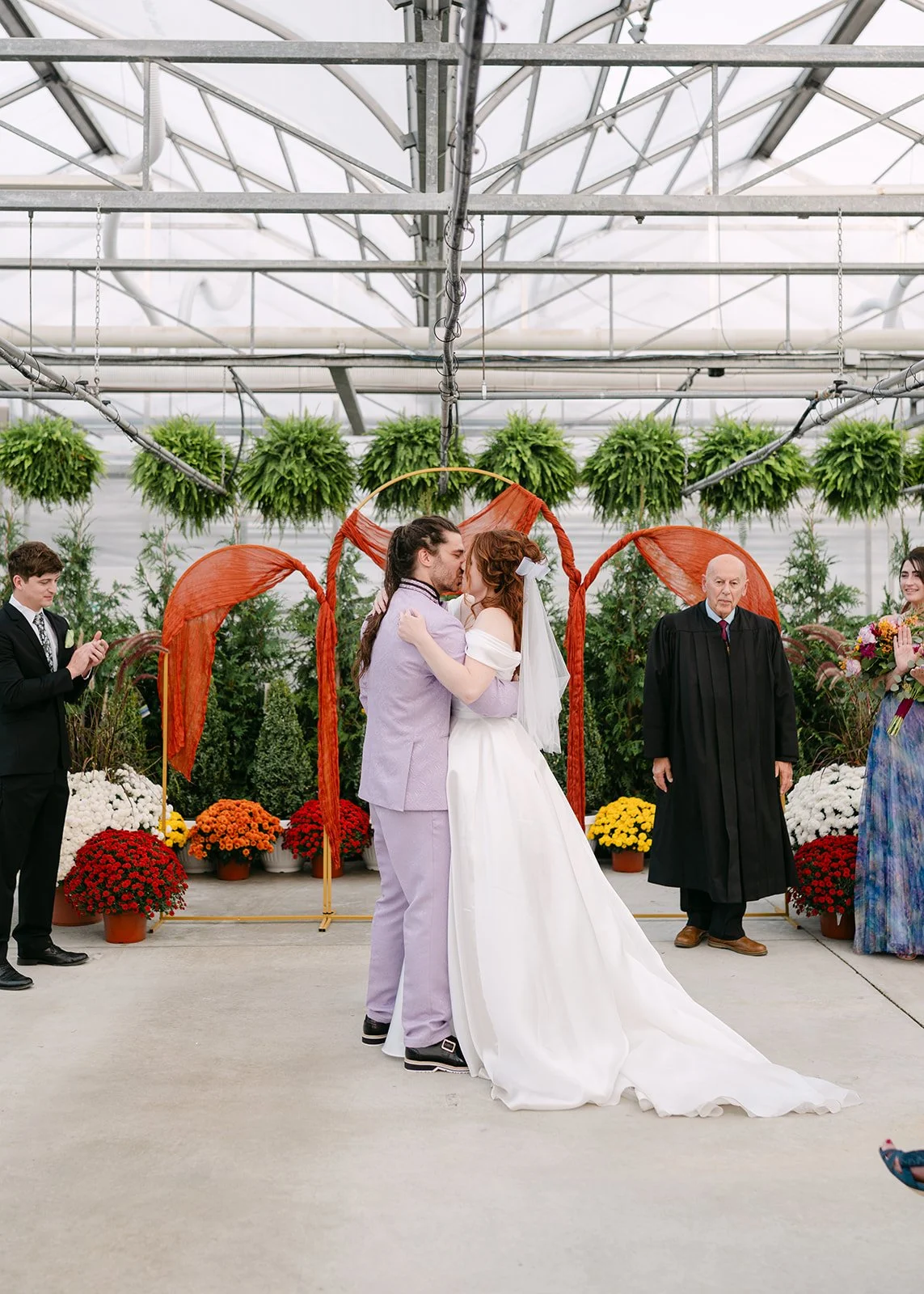 Bride and groom kissing at the altar during Abele Greenhouse wedding ceremony in Saginaw, Michigan.
