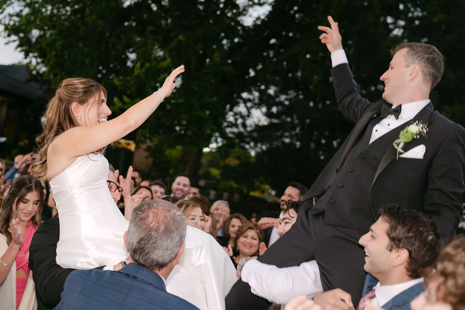 A photo of a bride and groom lifted into the air on the dance floor, having the time of their lives.