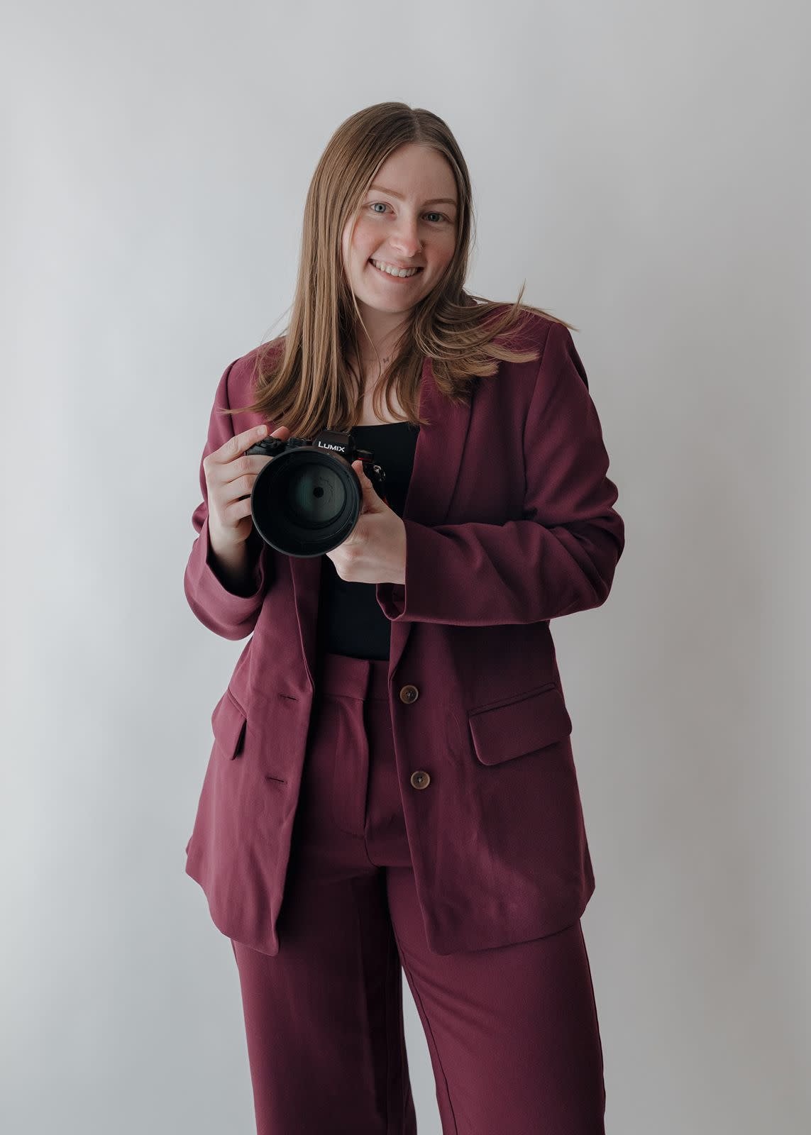 Alaina, owner of Alaina Miller Photography smiling and holding her camera for brand photos.