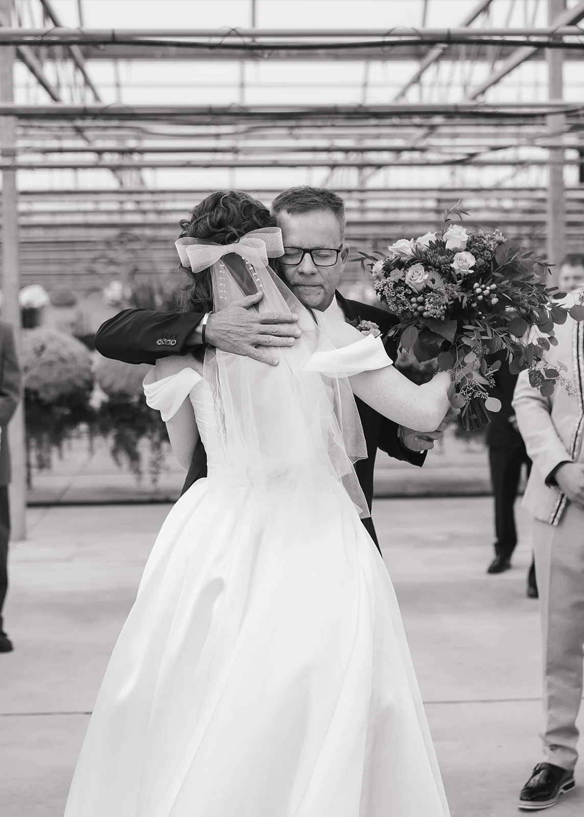 Bride hugging her father during ceremony at Abele Greenhouse wedding venue in Saginaw, Michigan.