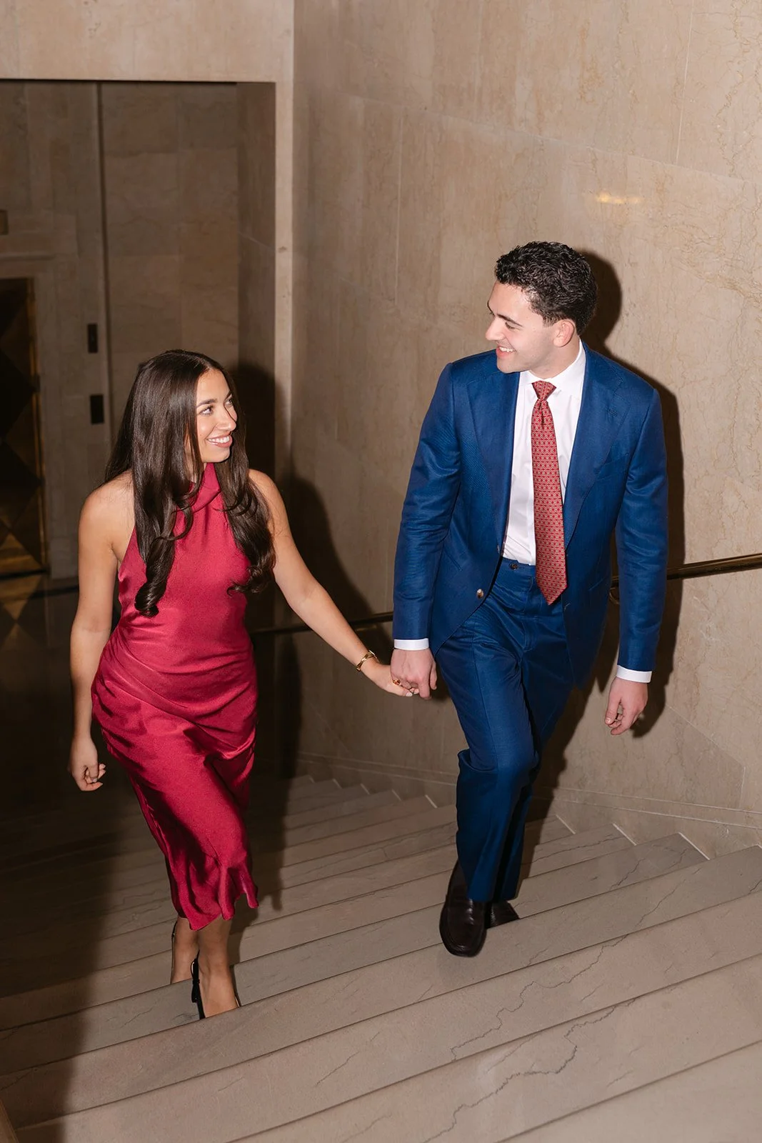 Couple holding hands and walking up the stairs together.