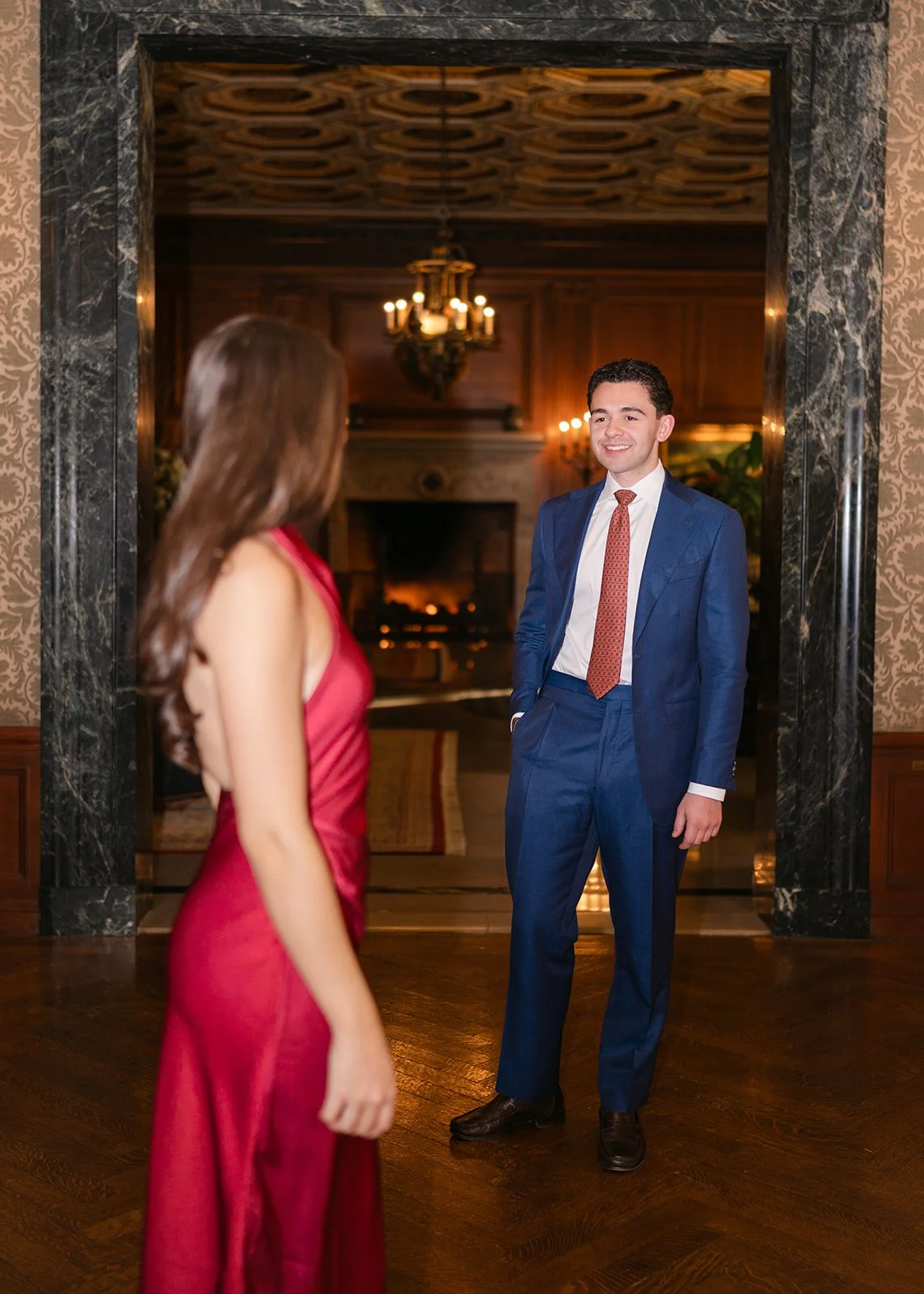 Couple looking at one another from a distance inside The Detroit Athletic Club for their elegant Detroit engagement photos,