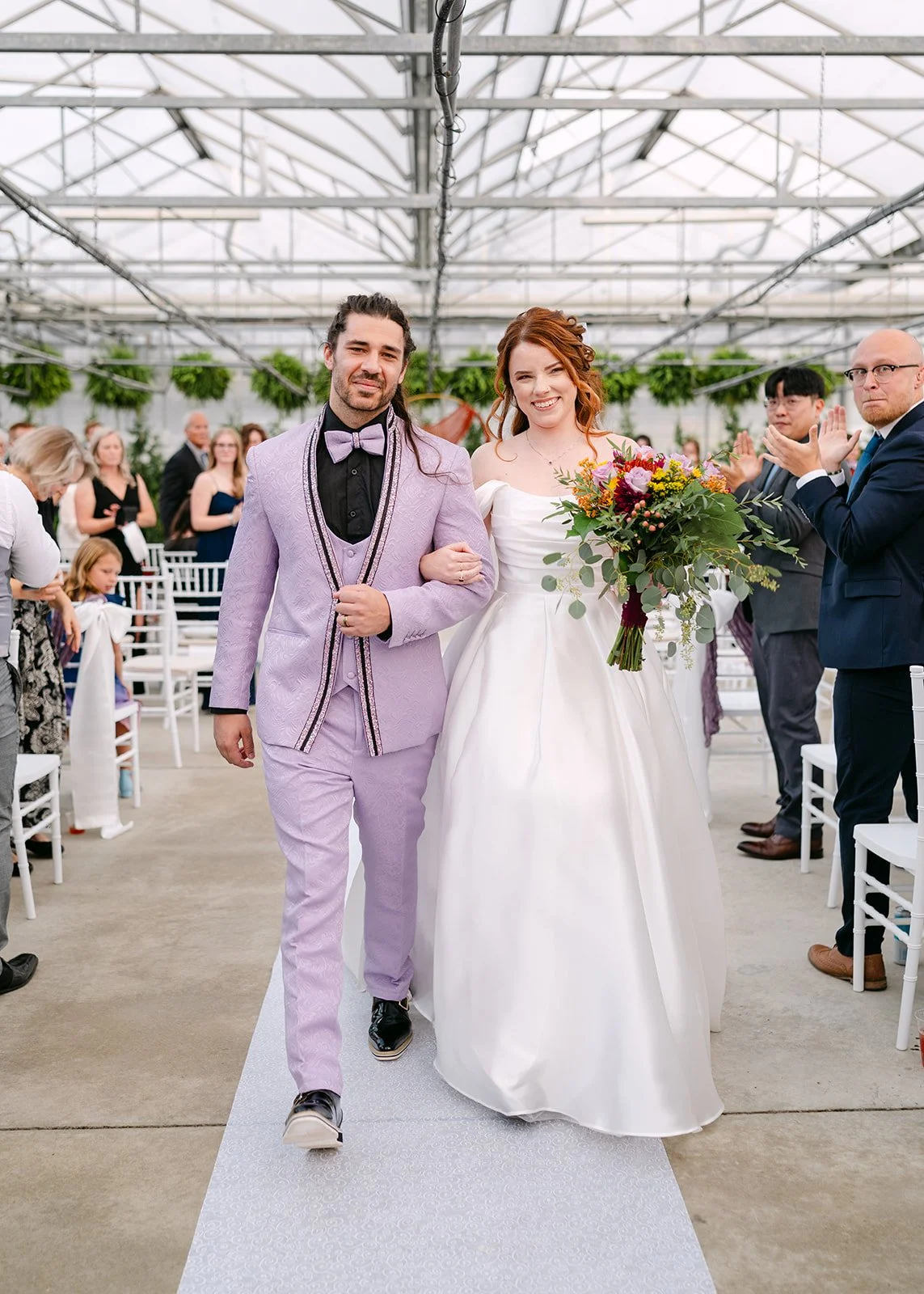 Bride and groom walking down the aisle after ceremony at Abele Greenhouse wedding venue in Saginaw, Michigan.