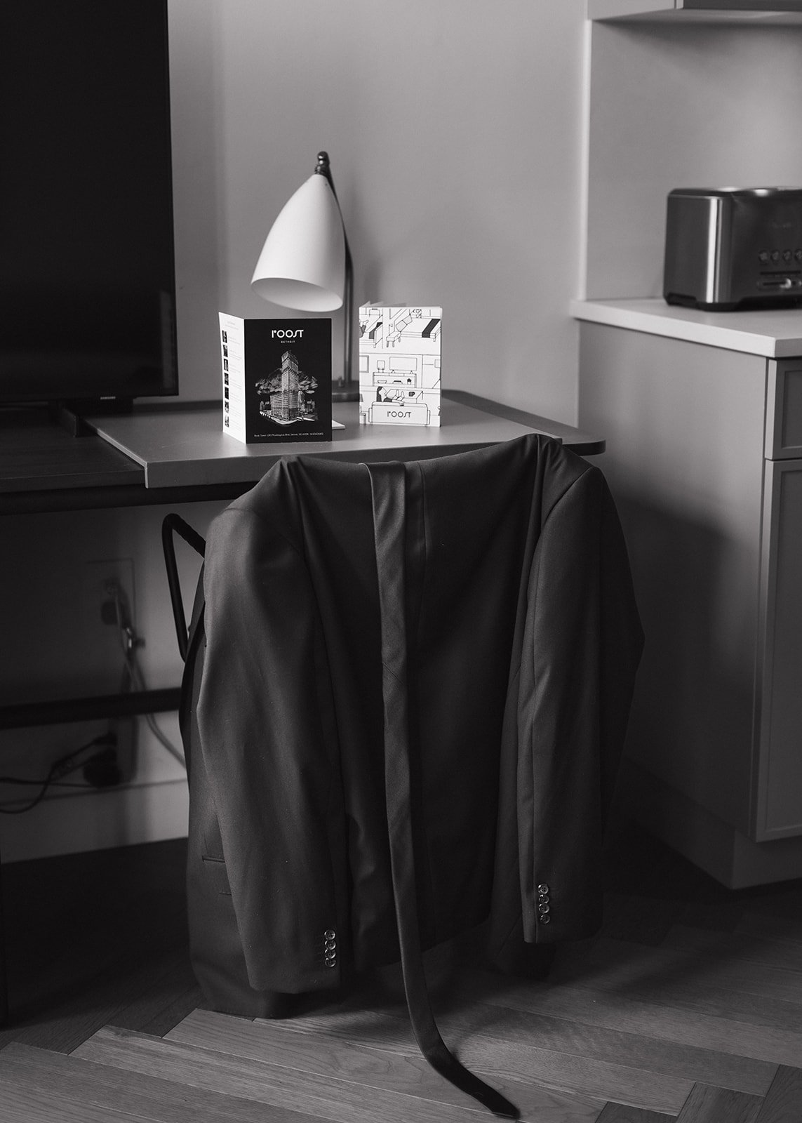 Black and white photo of the grooms suit laying on a chair inside ROOST Detroit.