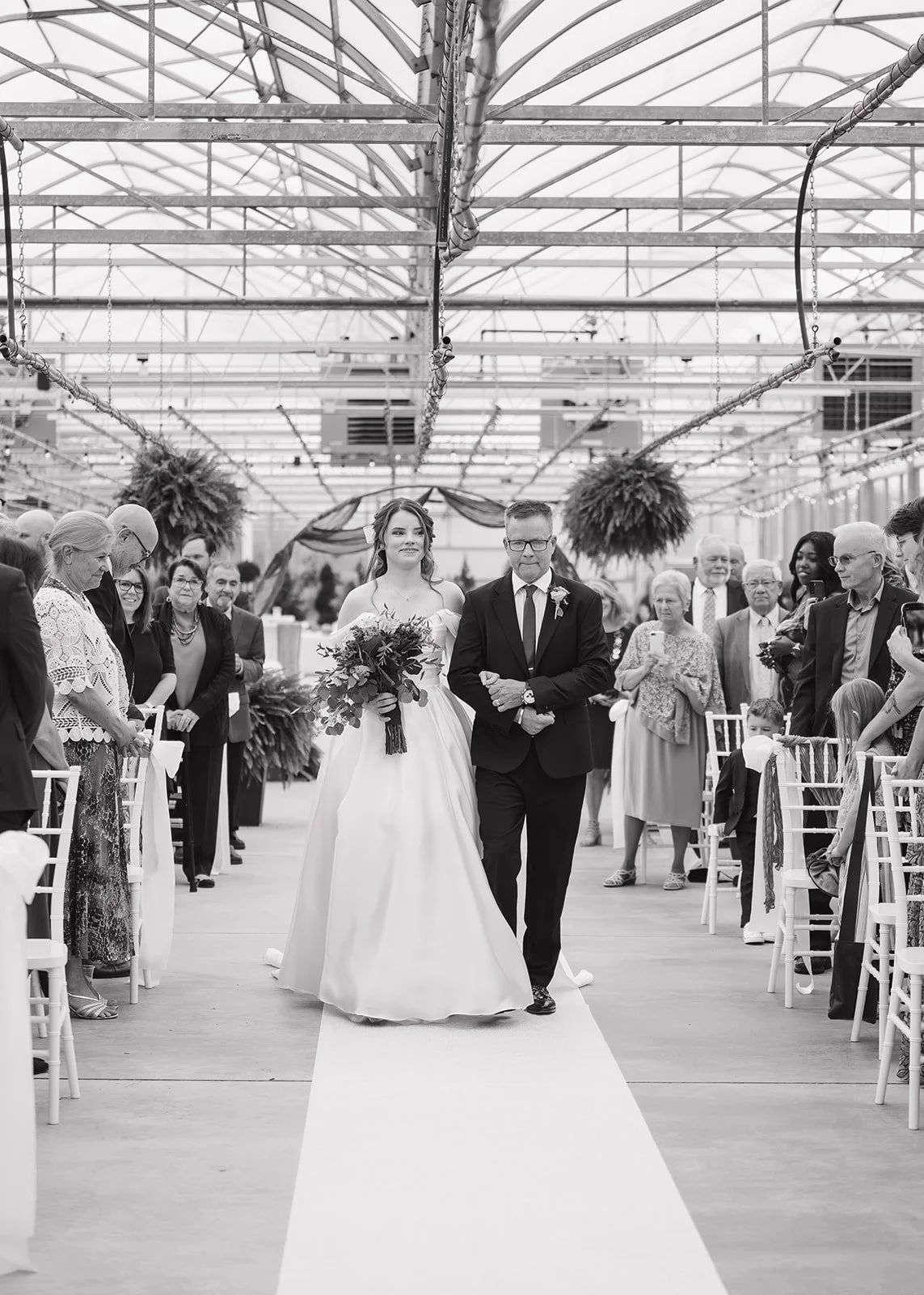 Bride walking down the aisle during Abele Greenhouse wedding ceremony in Saginaw, Michigan.