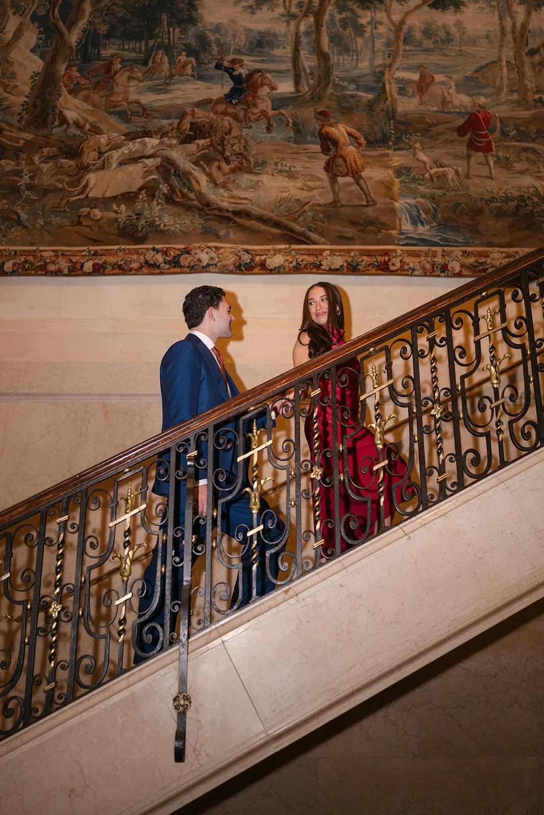 Couple walking up the stiarcase inside The Detroit Athletic Club for their elegant Detroit engagement photos.
