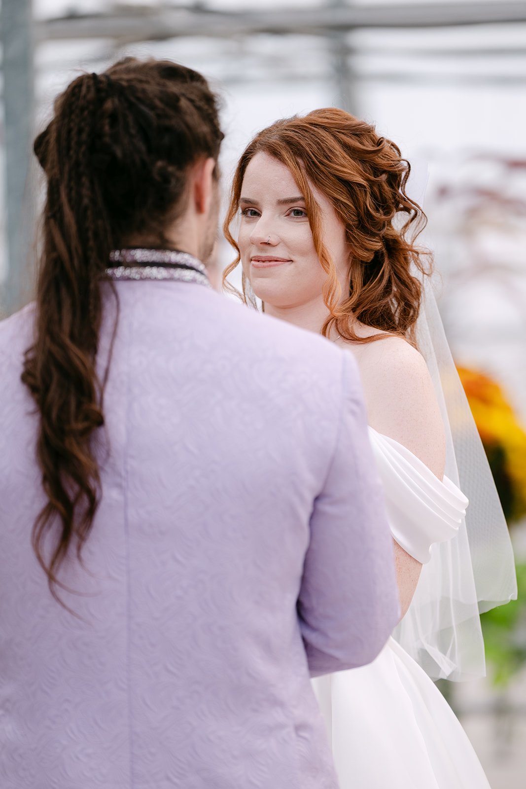 Close up shot of the bride smiling at the groom during their greenhouse wedding ceremony.