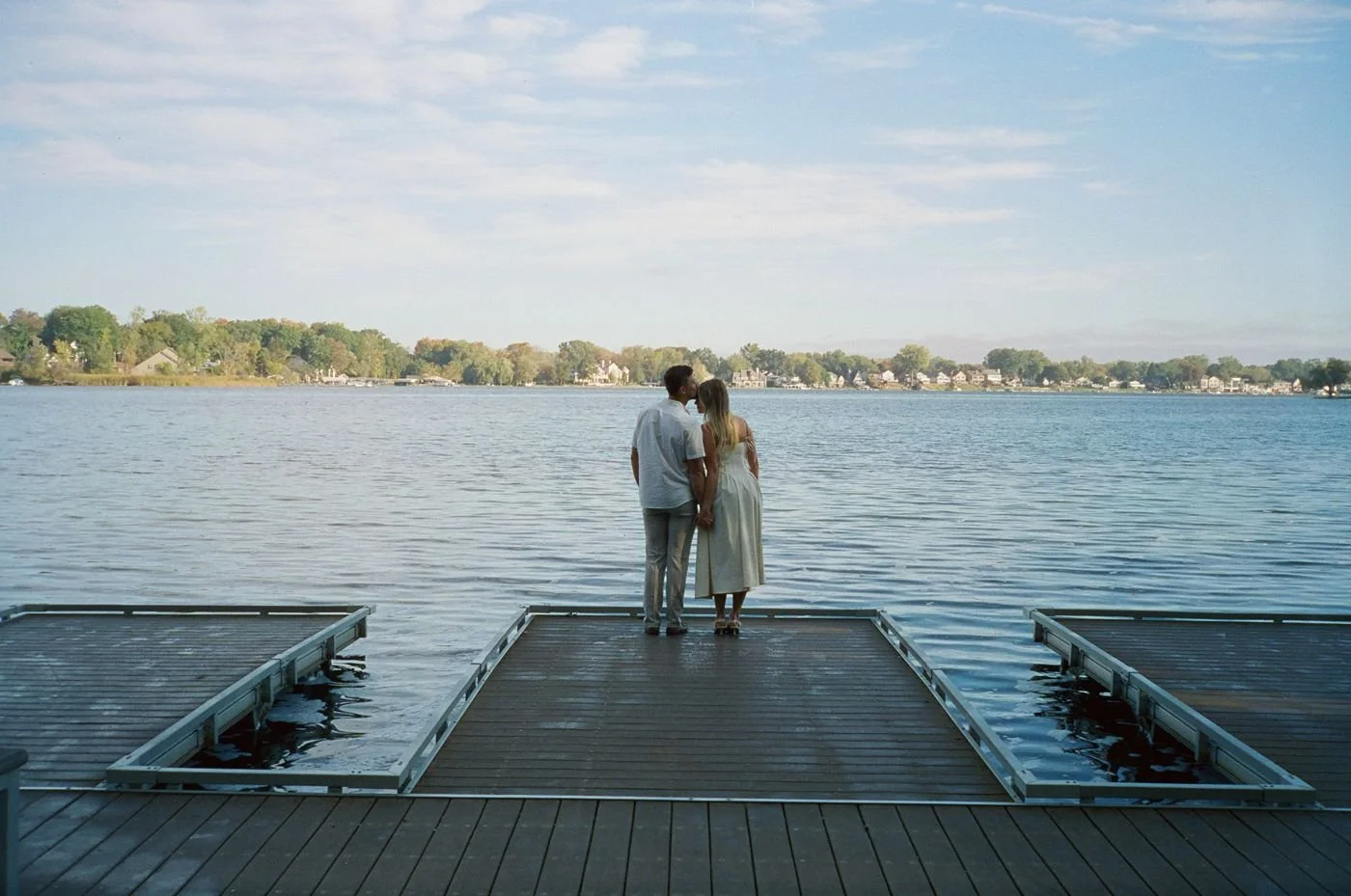 A couple gazes at each other through ornate carved metal doors, with the woman touching the man's chest, both smiling softly.