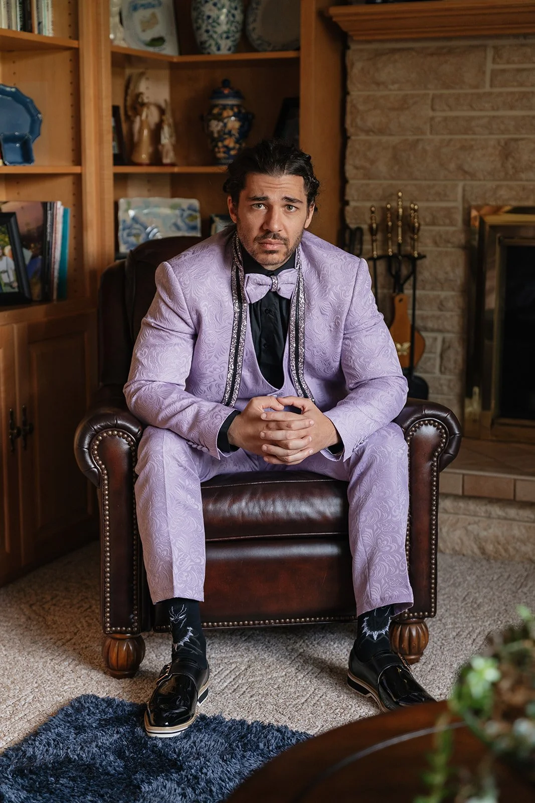 Indoor portrait of the groom sitting in a leather chair.