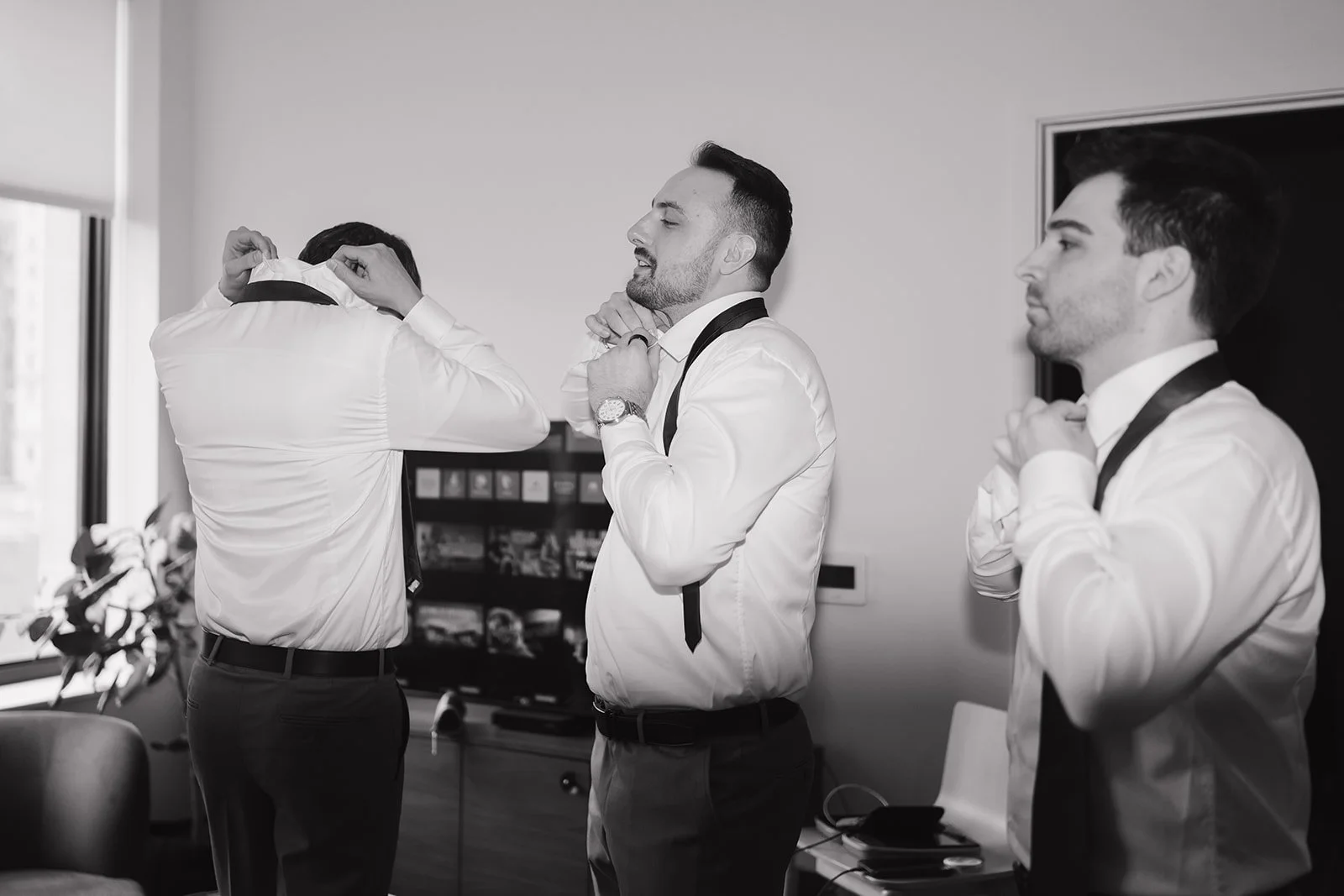 Black and white photo of the groomsmen getting ready in a suite at ROOST Detroit.