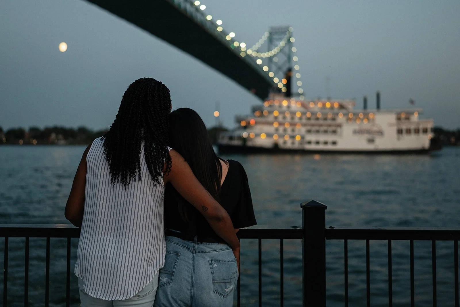 Couple admiring a yacht in the water during their Detroit engagement photos.