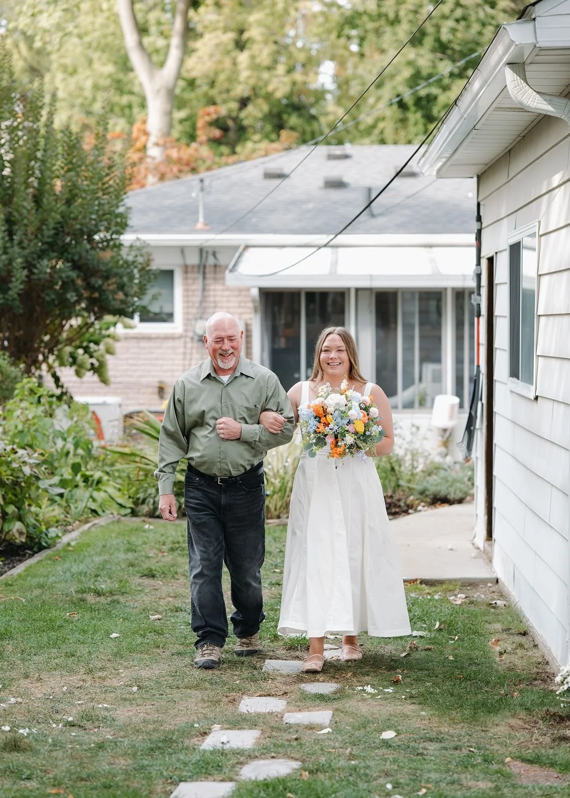 A father walking his daughter down the aisle at their backyard wedding venue.