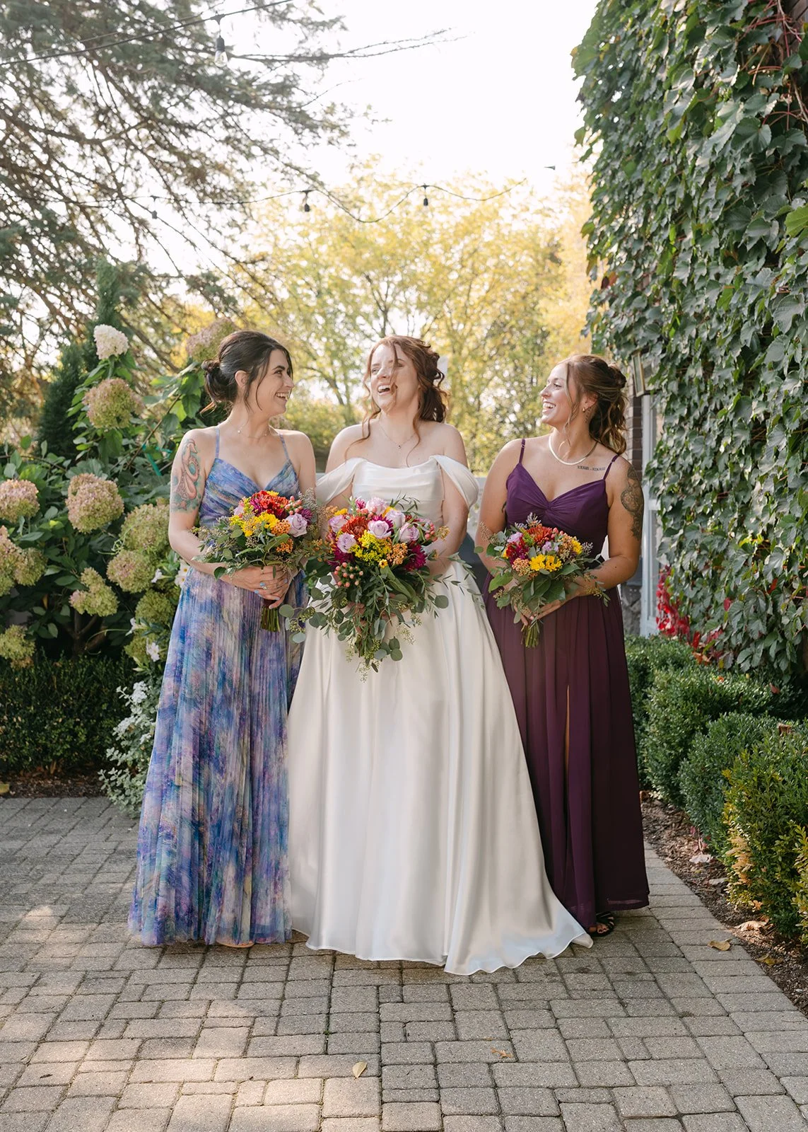 Bride laughing outdoors with her bridesmaids during portraits outside of Brownstone Haus in Frankenmuth, Michigan.
