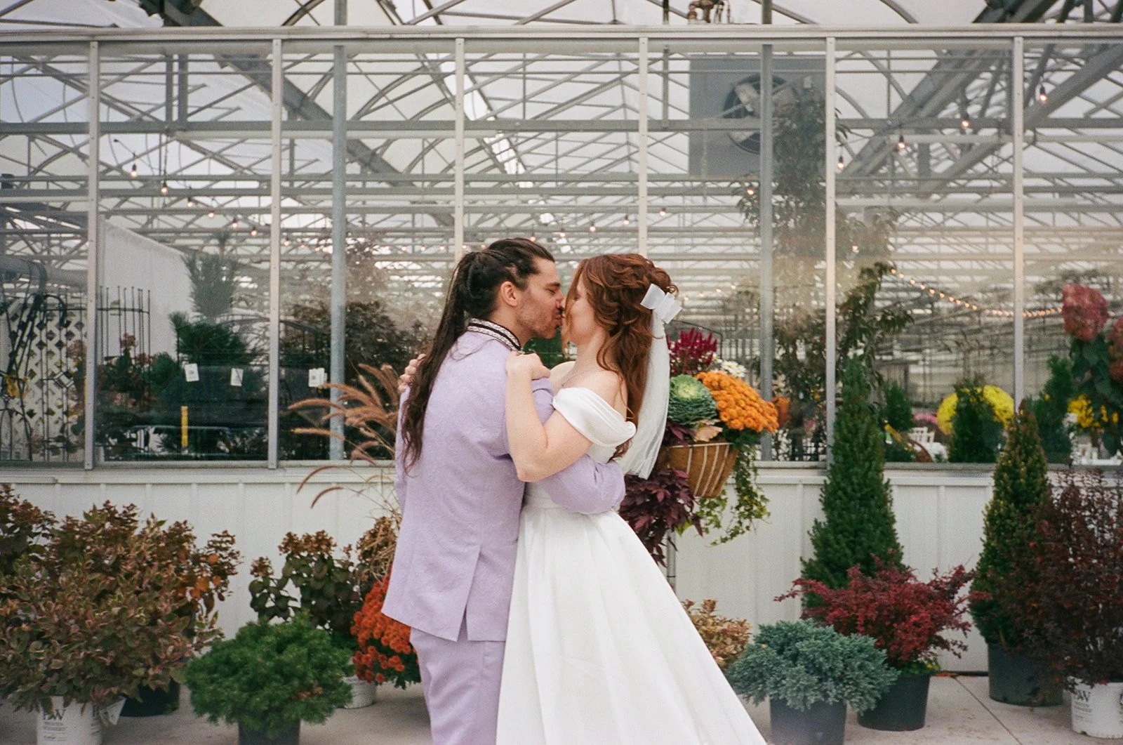 Film photo of a bride and groom kissing in front of Abele Greenhouse in Saginaw, Michigan.